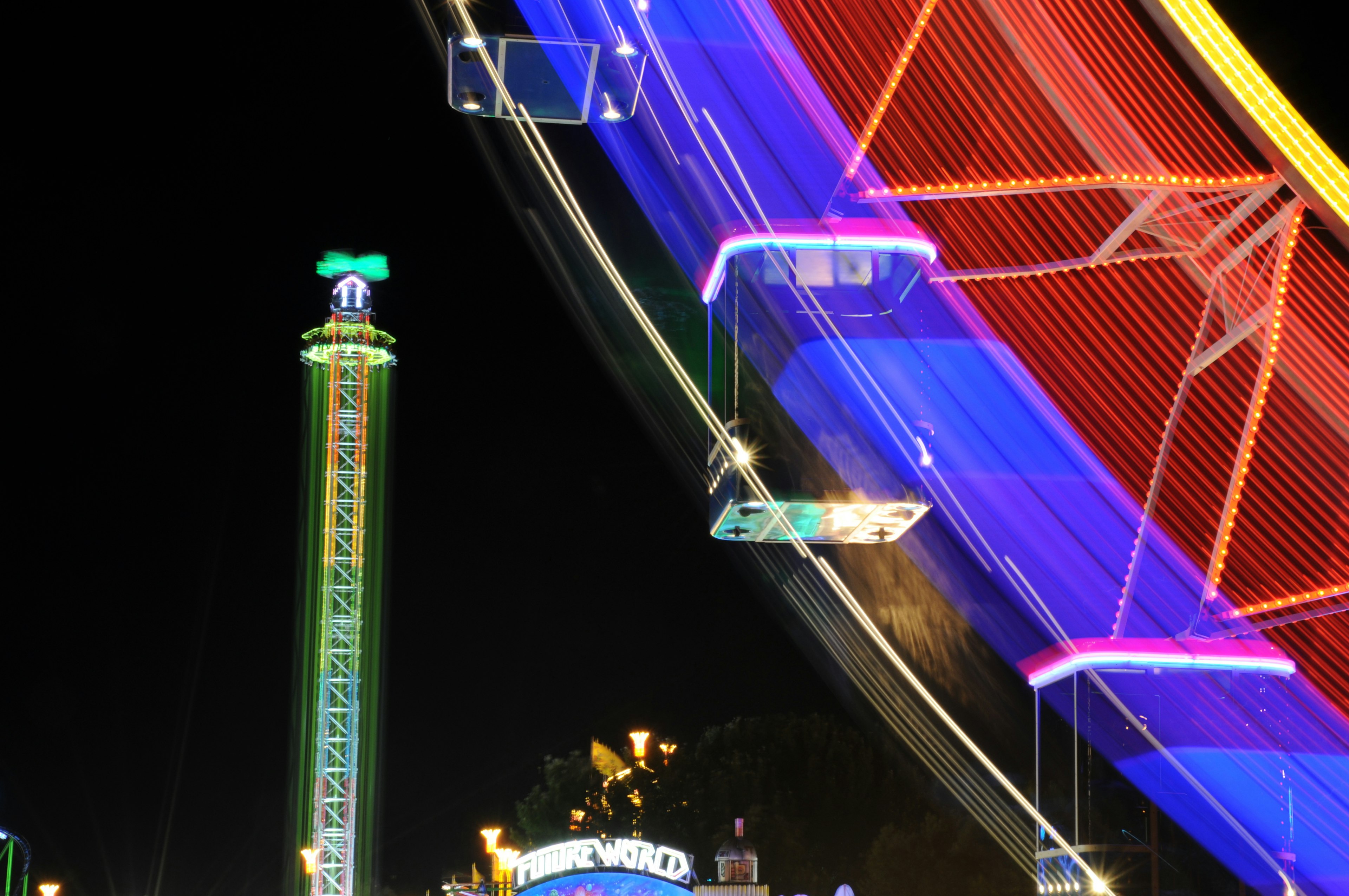 Brillantes luces de neón de una noria y una torre de noche