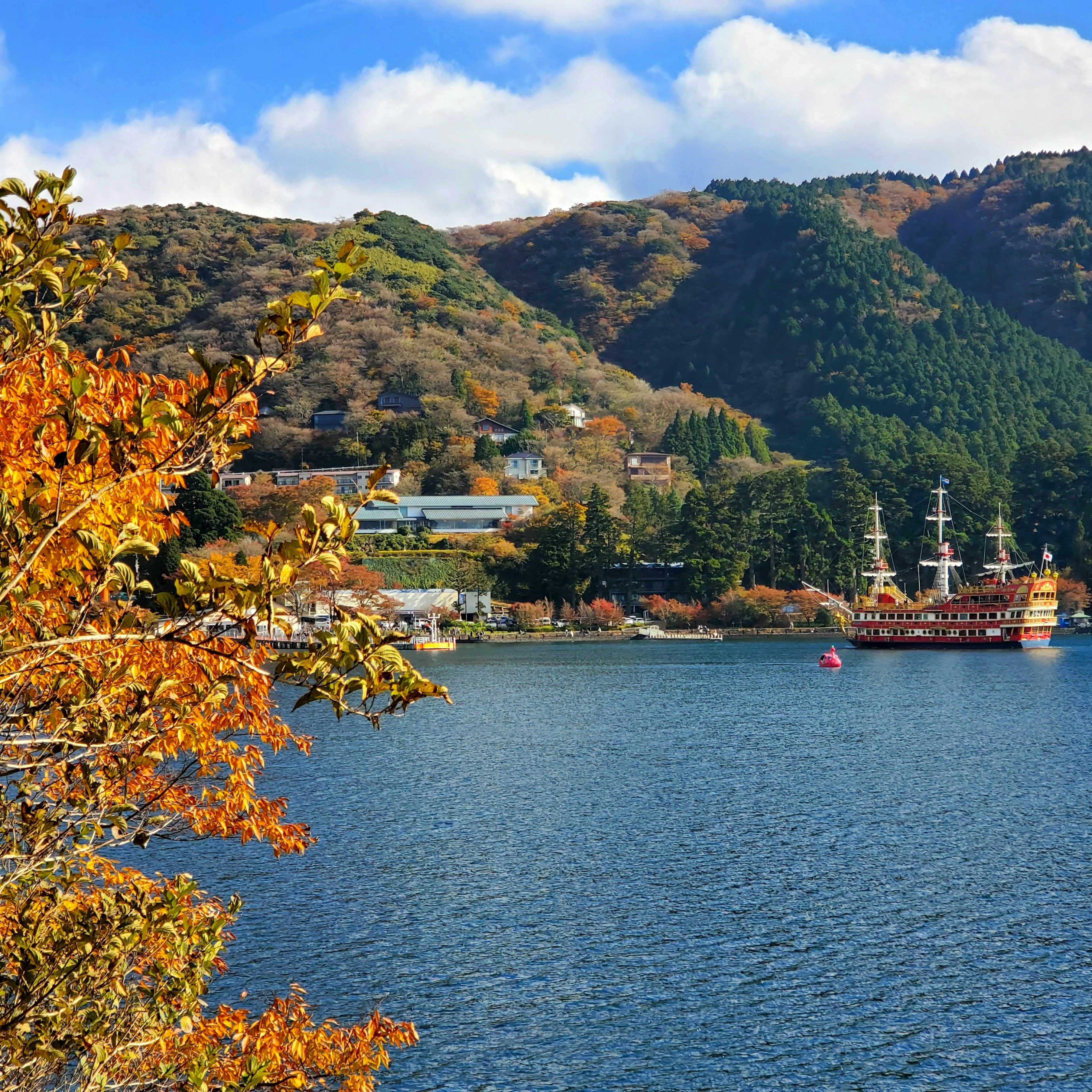 Malersicher Blick auf einen See umgeben von Bergen in Herbstfarben mit einem liegenden Schiff