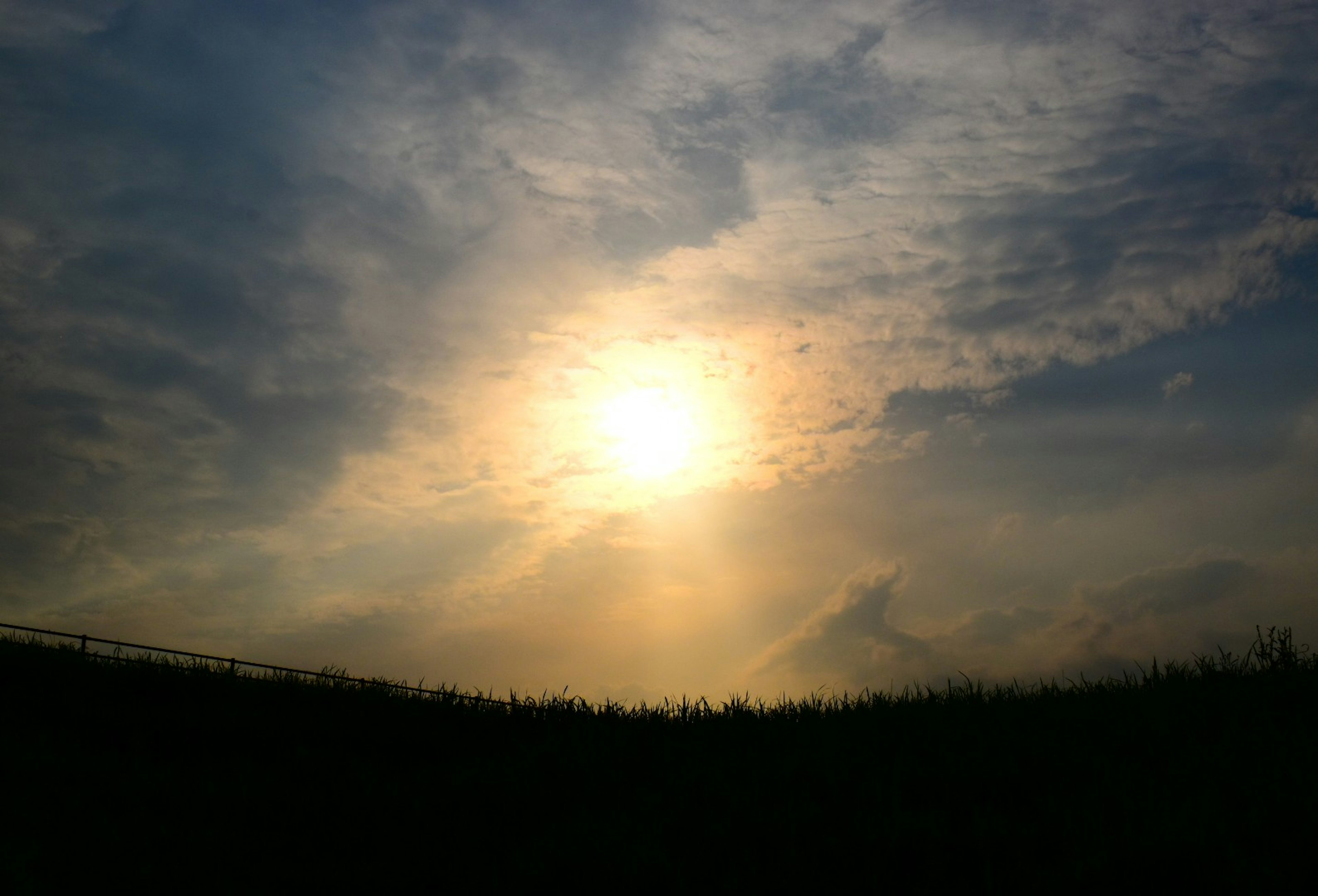 Silhouette of the sun against a cloudy sky