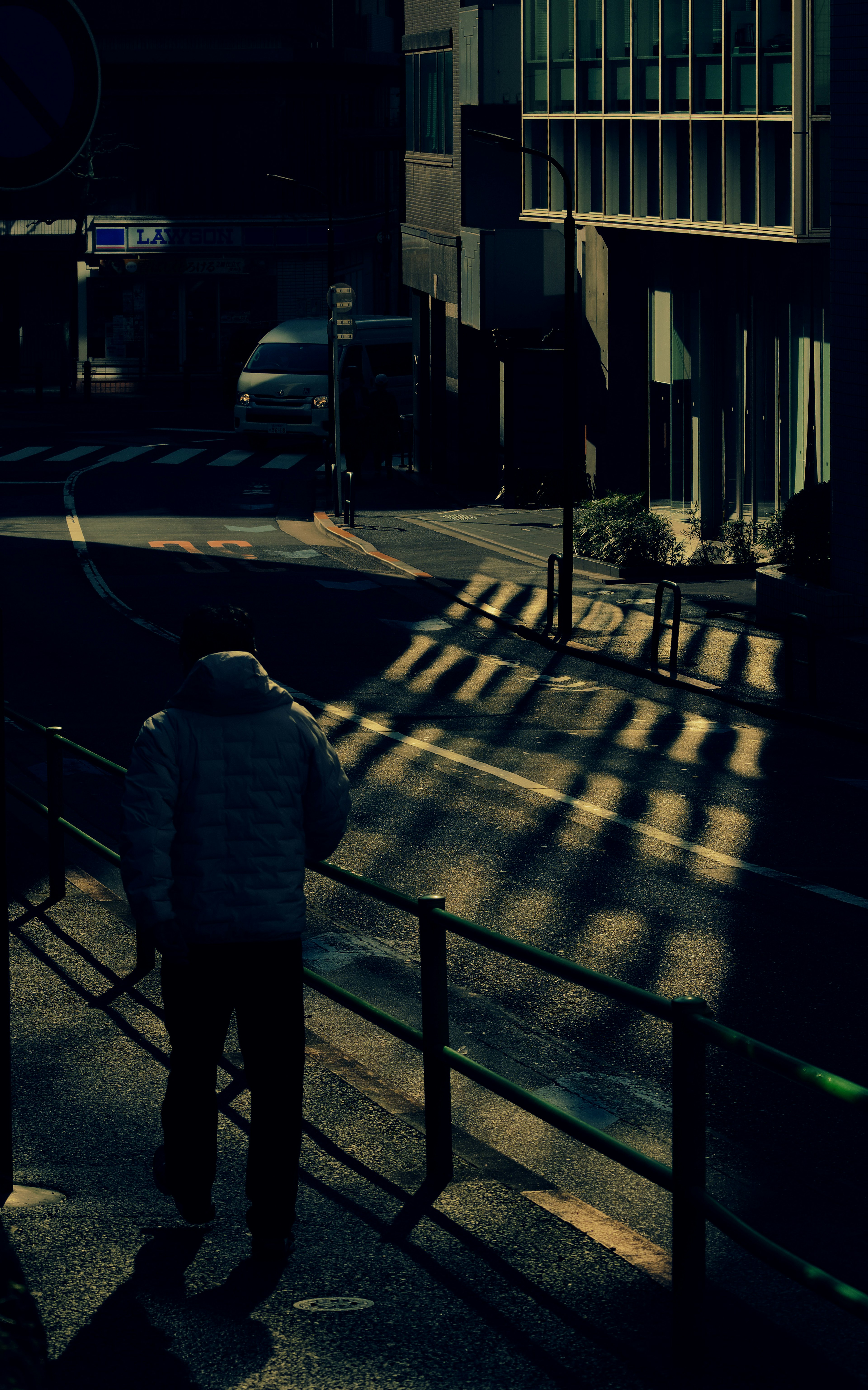 A person walking on a dark street with shadows and urban scenery