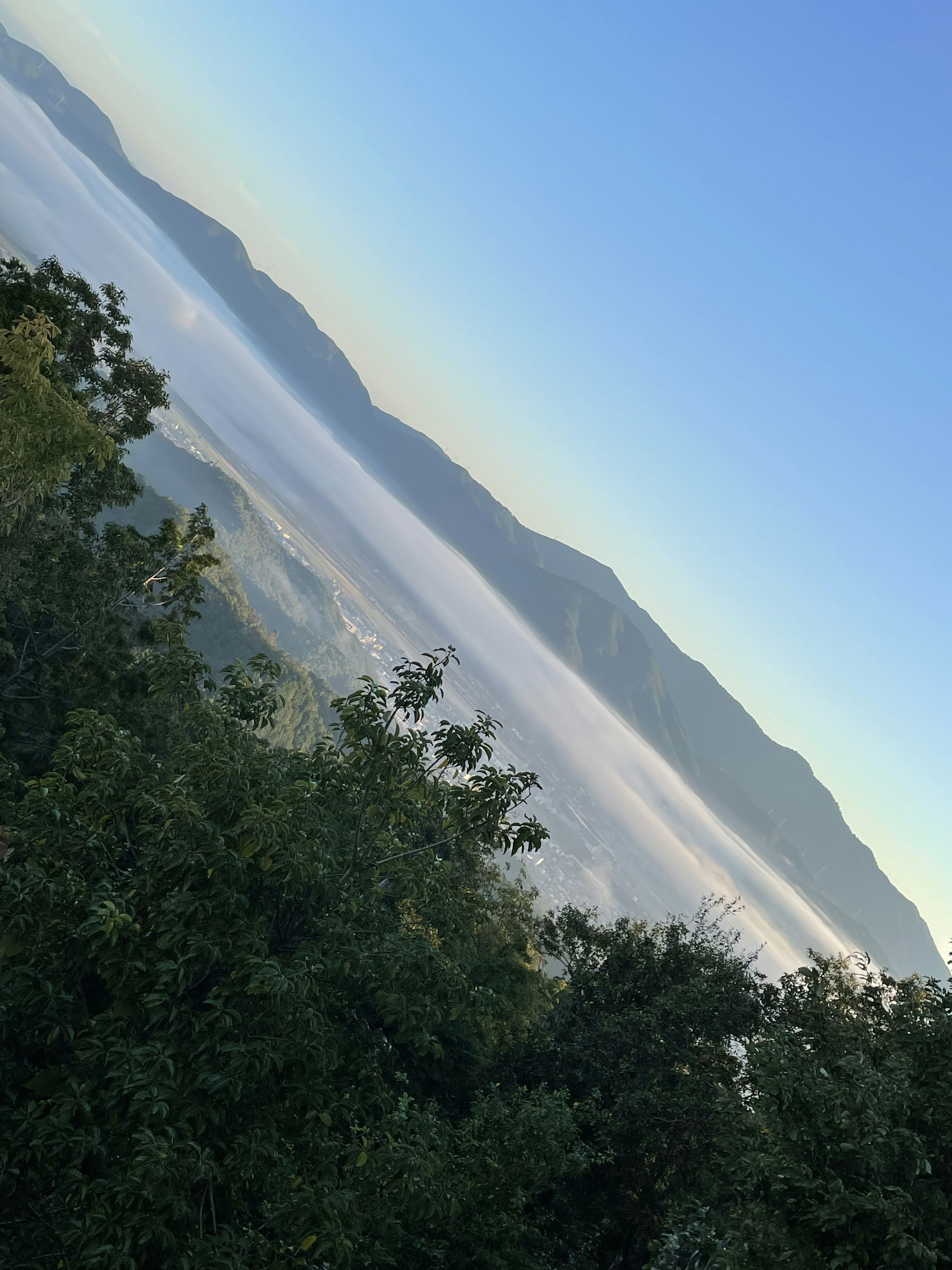 Pemandangan pegunungan yang diliputi kabut di bawah langit biru