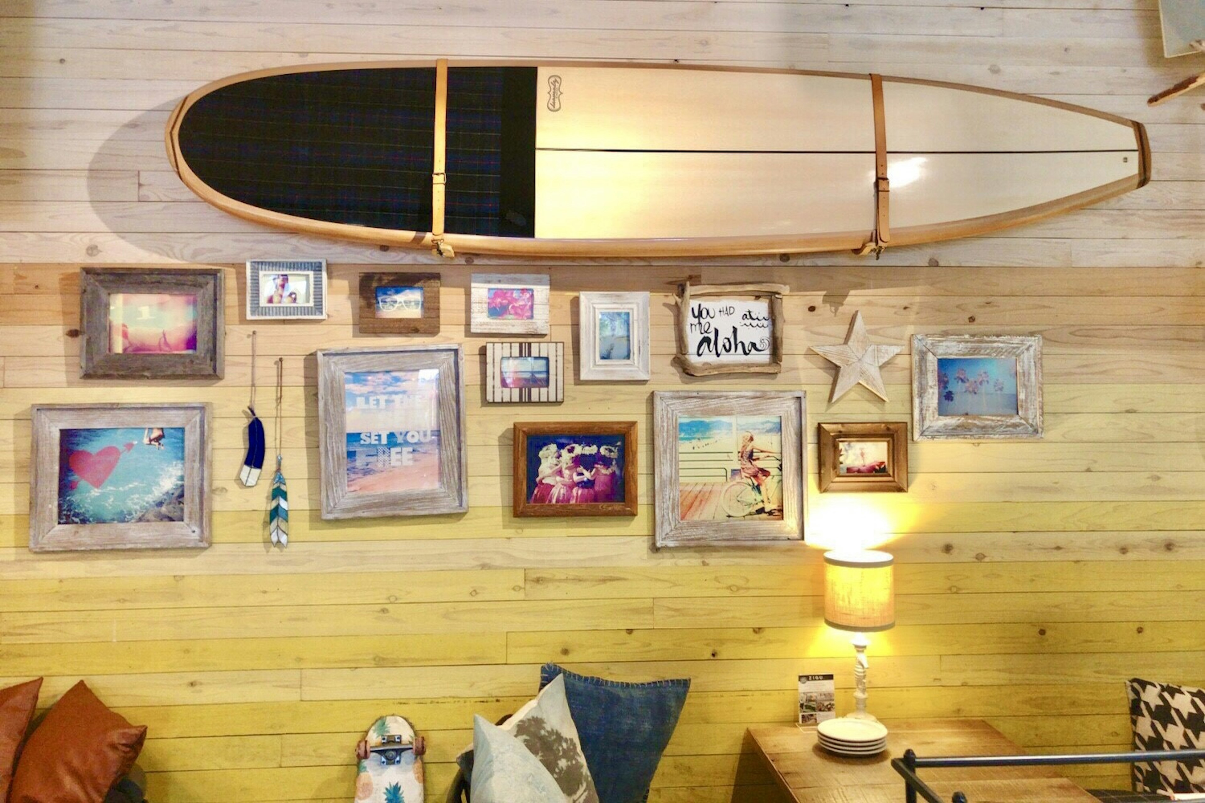 Wooden wall adorned with seaside-themed artwork and a surfboard