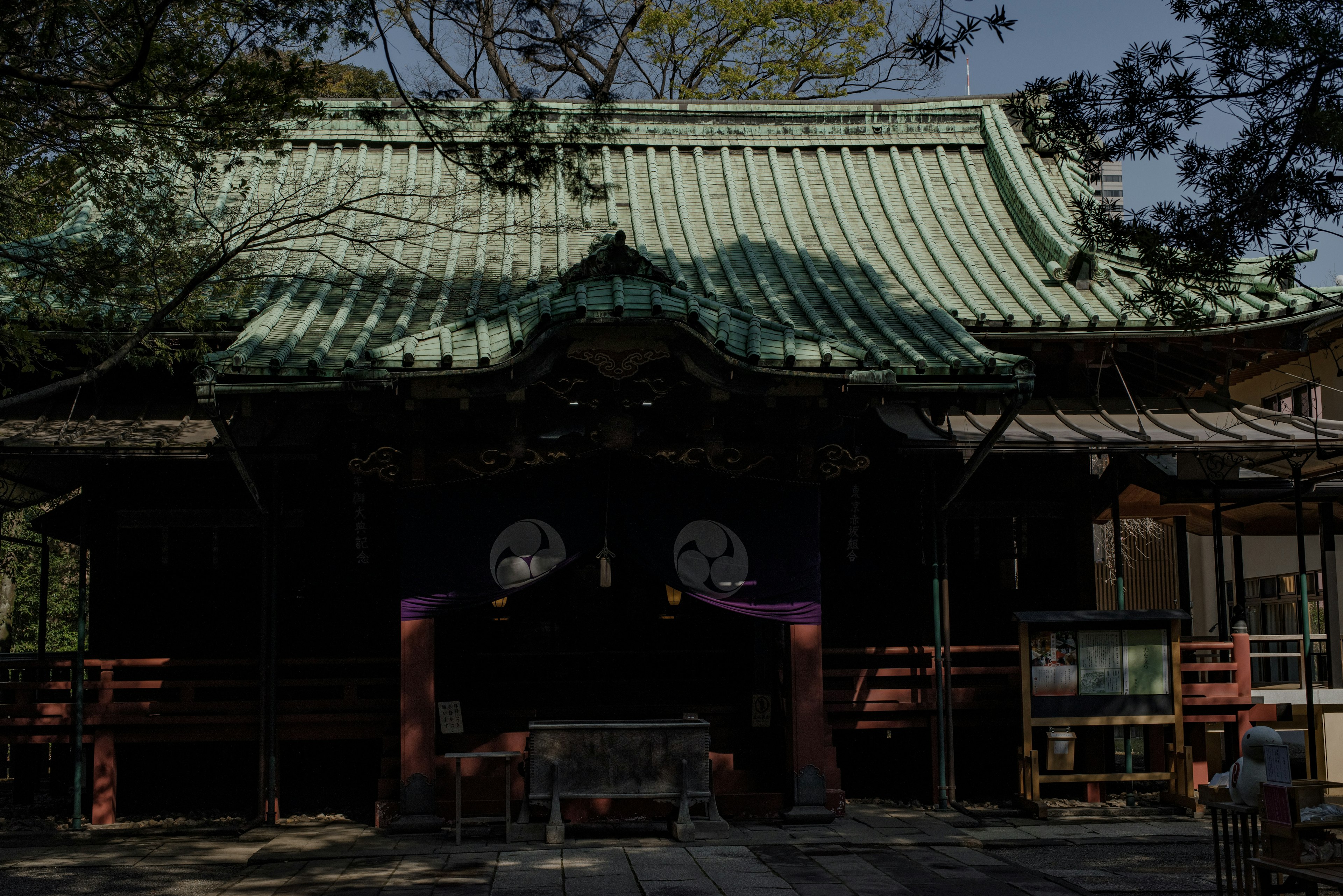 緑色の屋根を持つ神社の建物で、周囲に木々が茂っている
