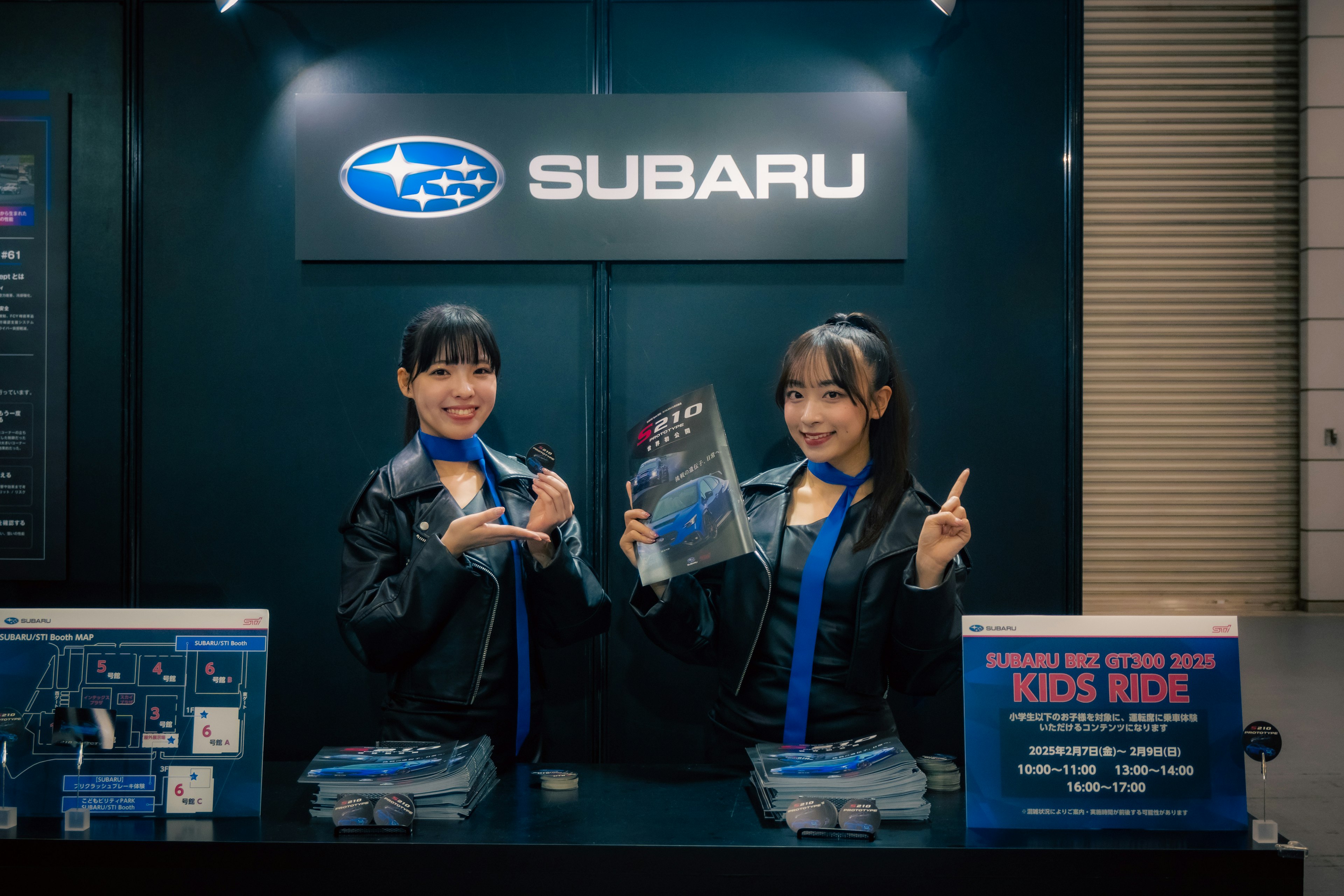 Dua wanita di stan Subaru memegang produk