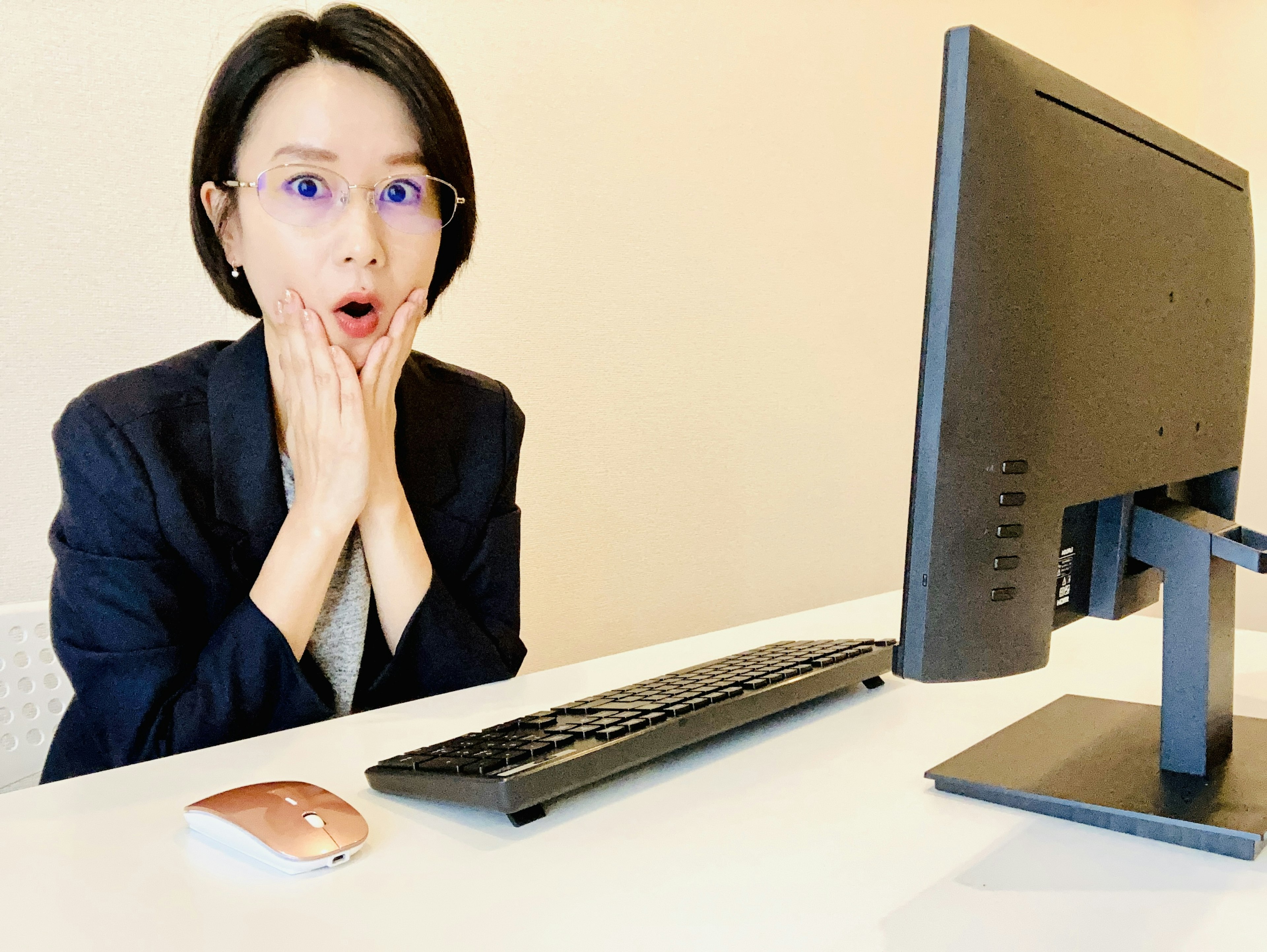 A surprised woman at a desk looking at a computer