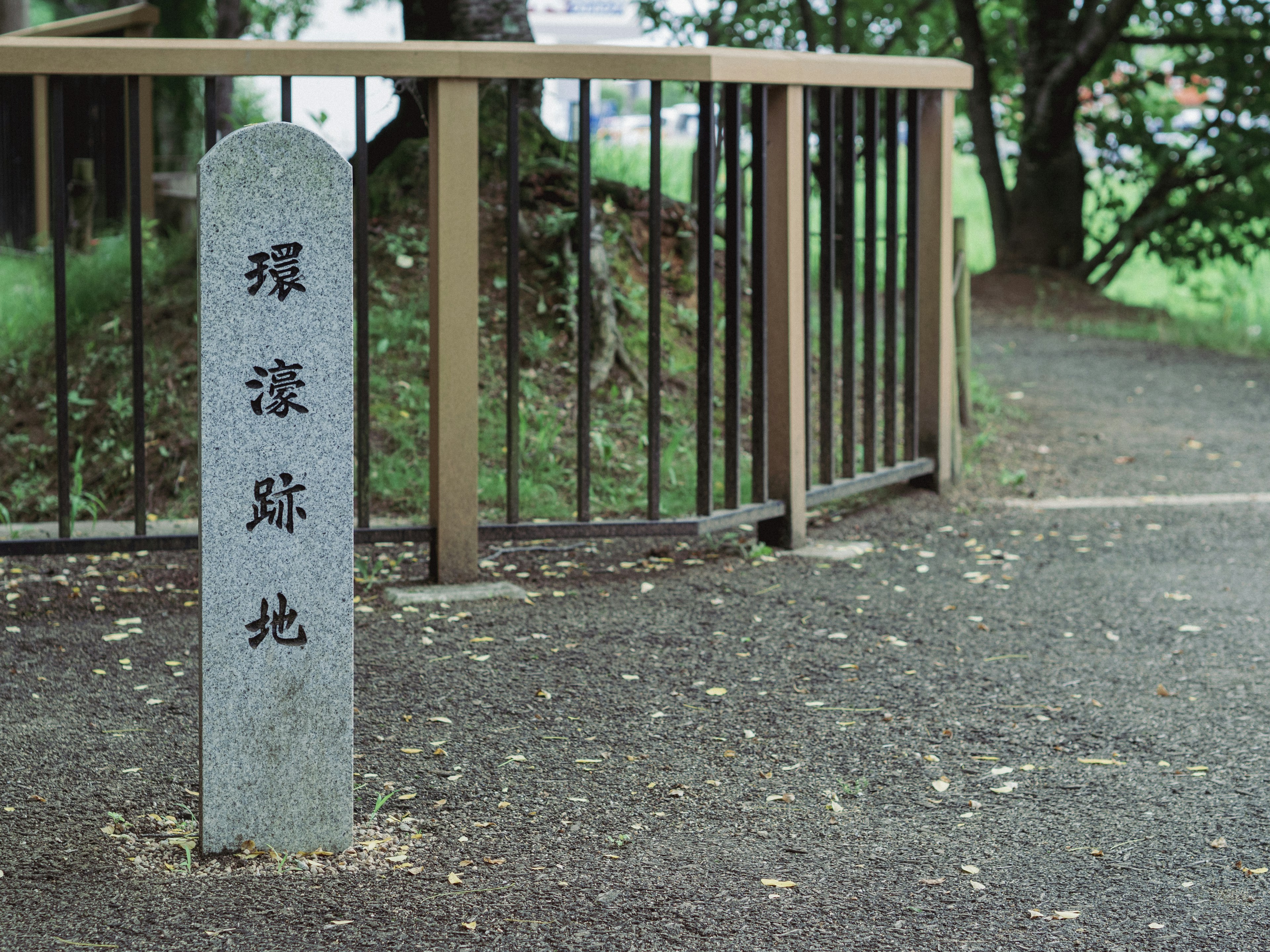 Stone marker at park entrance surrounded by green trees