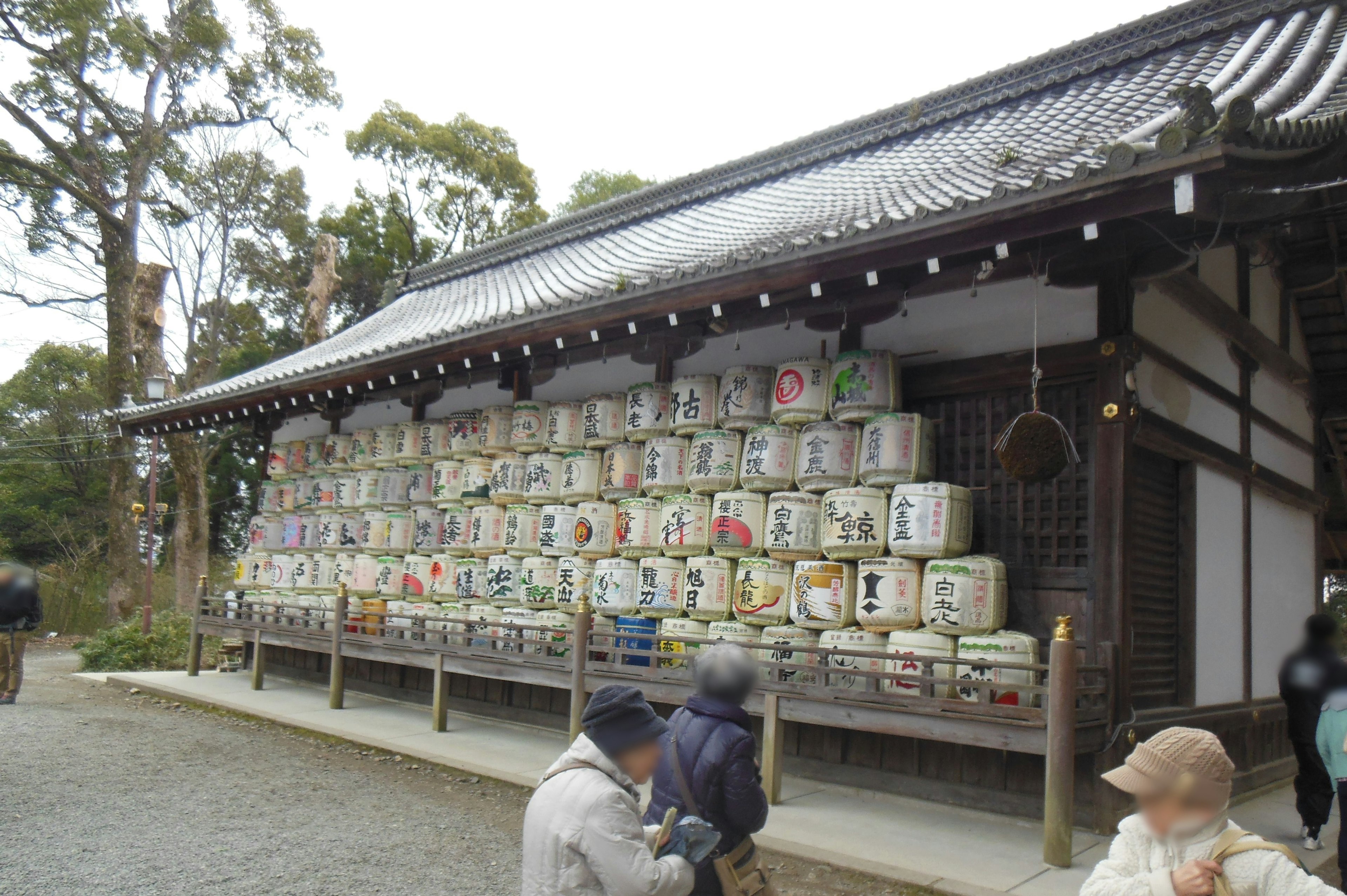 日本の寺院に並ぶお酒の樽と参拝者たち