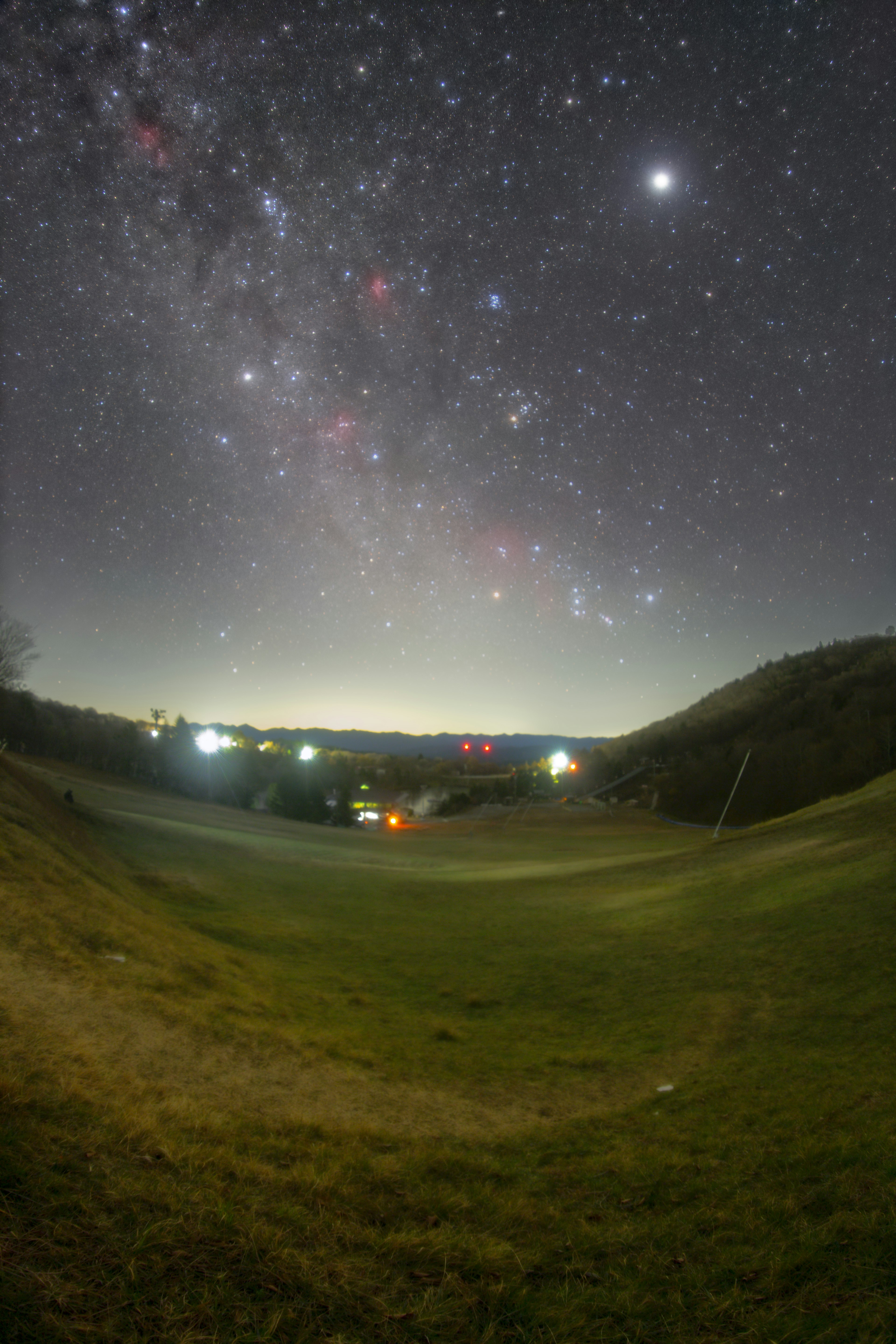 星空が広がる草原の風景 明るい星々と遠くの光が見える