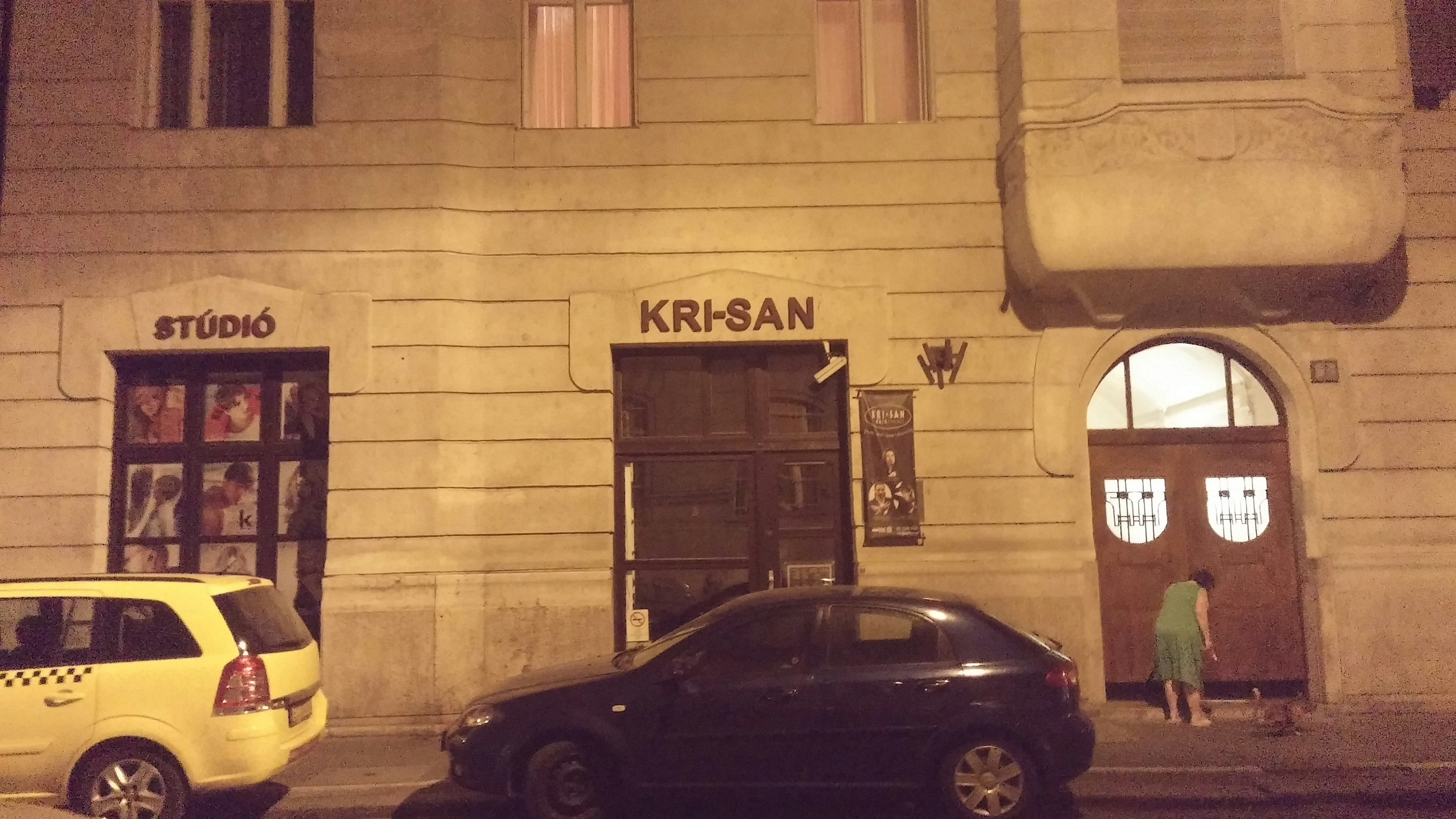 Night scene featuring the Krisan establishment and a yellow taxi