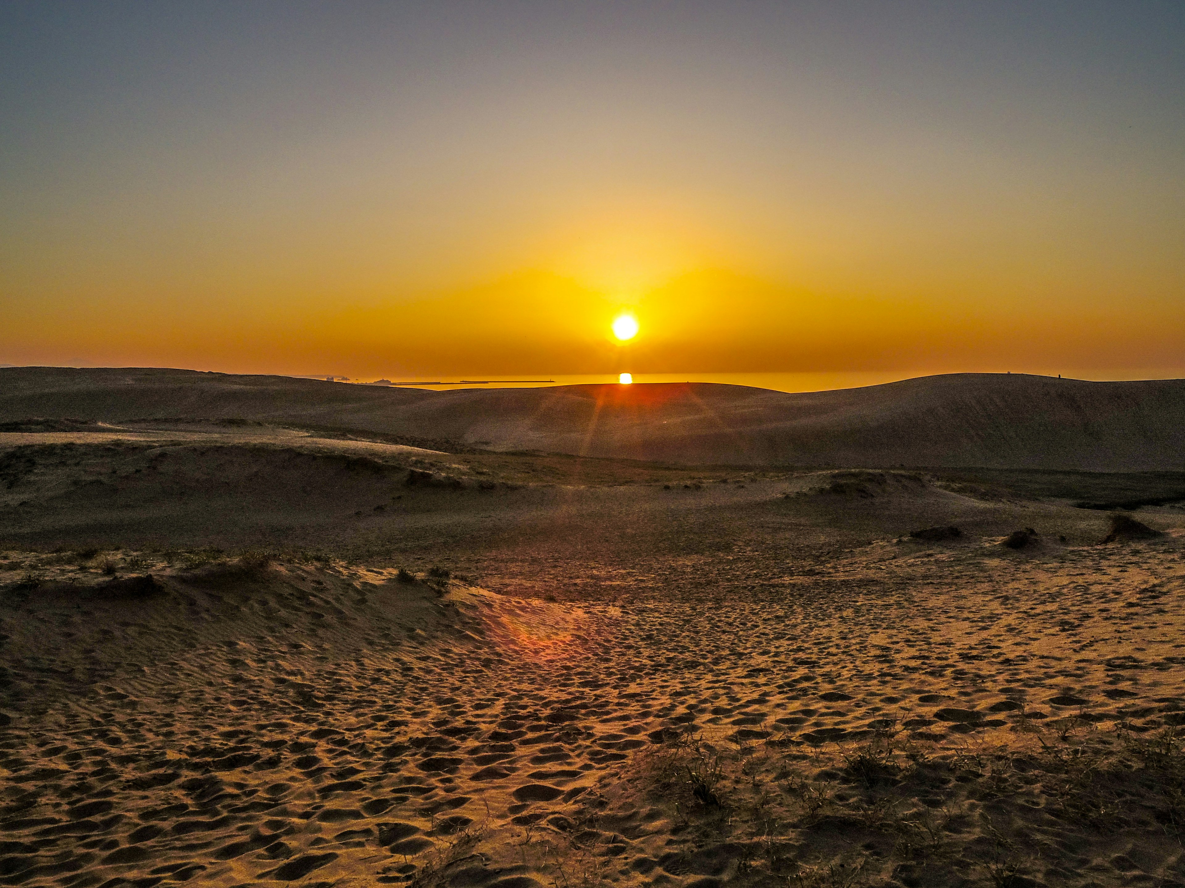 Hermoso paisaje de atardecer en el desierto cielo naranja y dunas de arena sombreadas