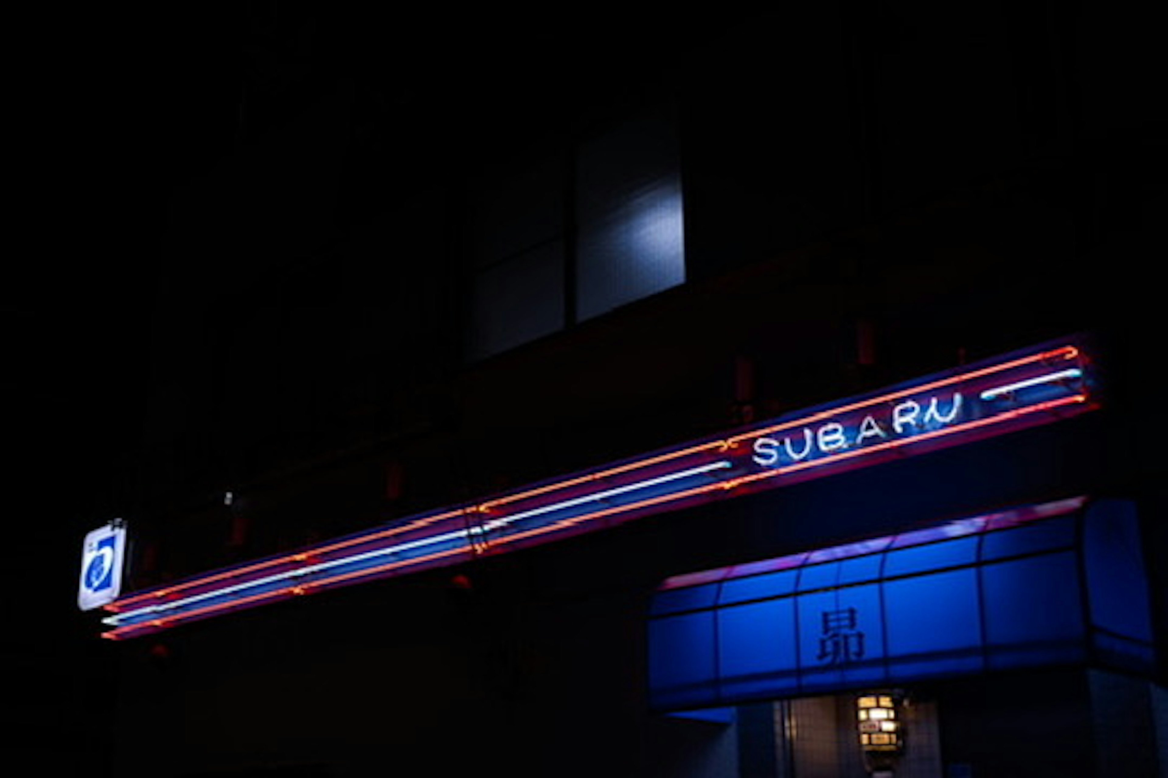 SUBARU sign illuminated at night with blue lighting