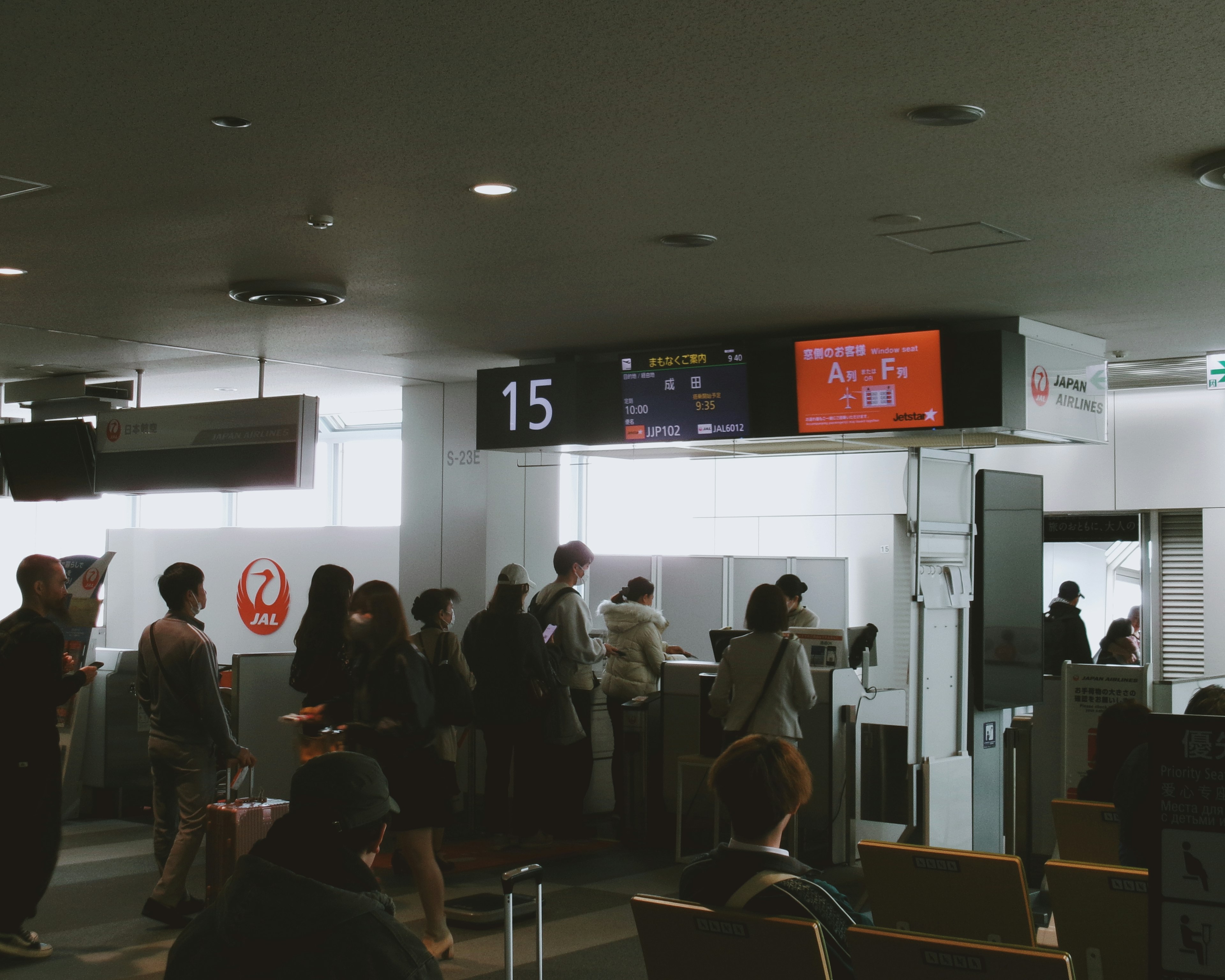 공항 게이트 15에서 기다리는 승객들과 정보 디스플레이 화면