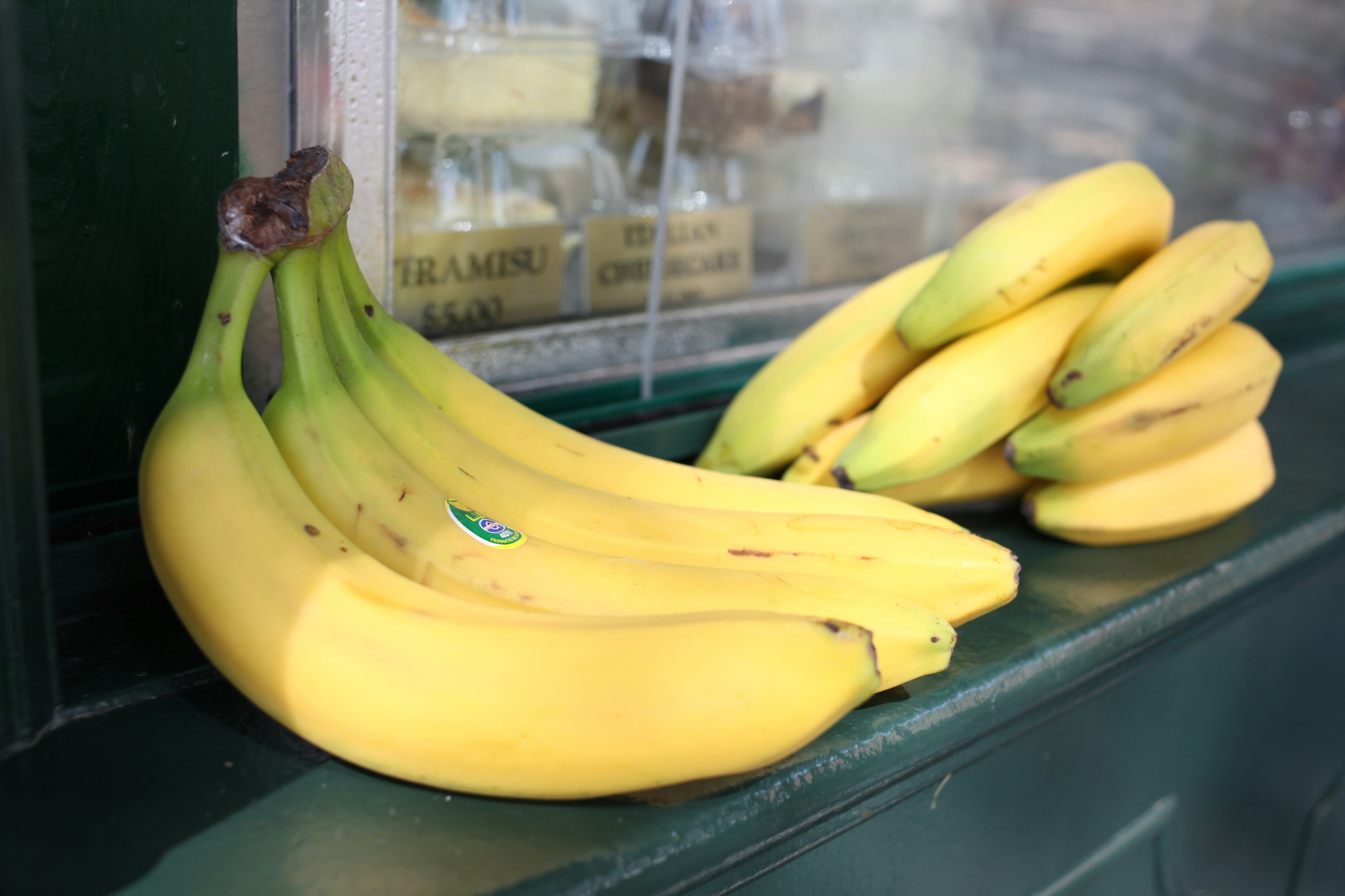 Un manojo de plátanos maduros colocado sobre una mesa verde