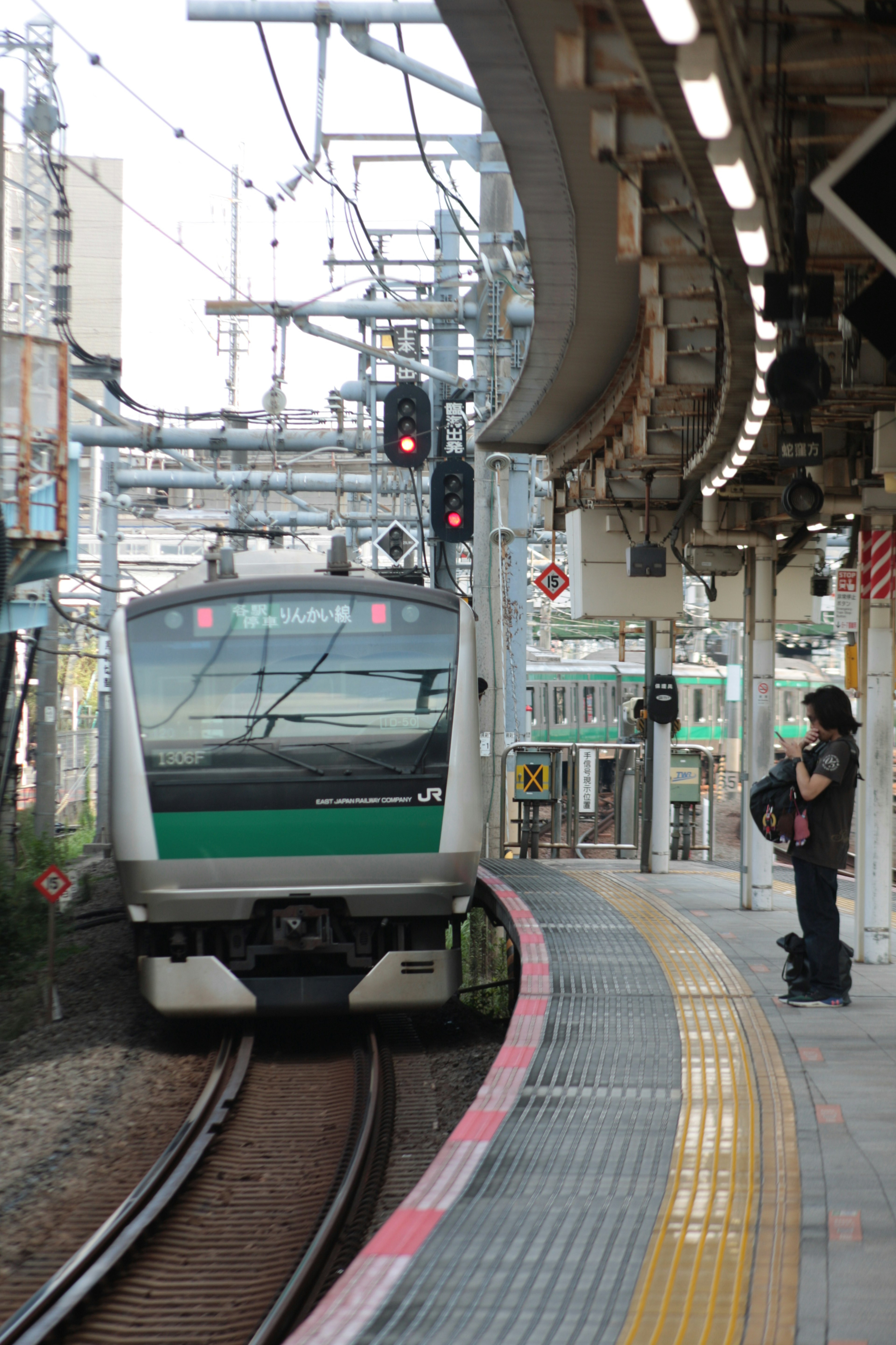 Train arriving at a station platform with a waiting passenger