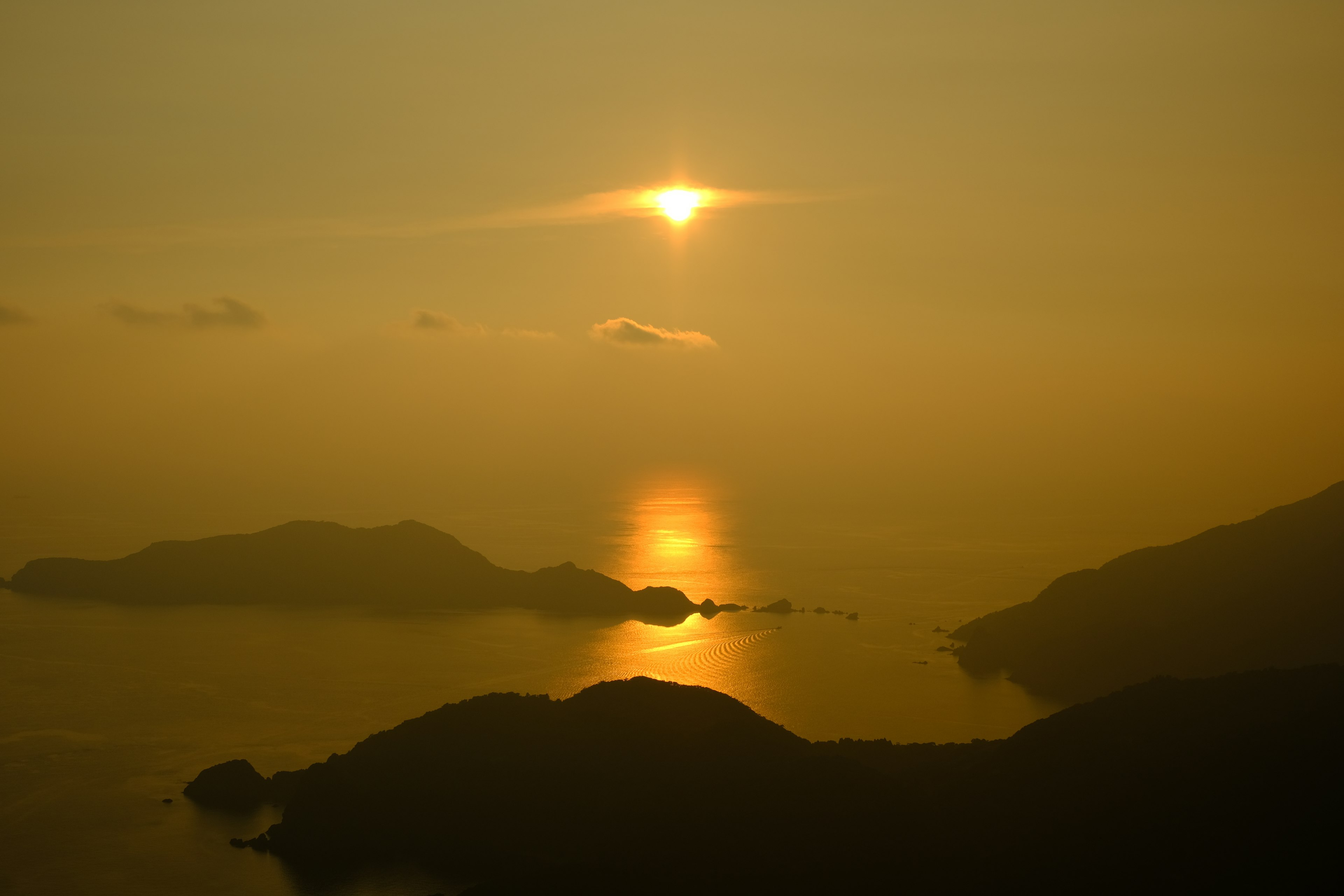 Magnifique coucher de soleil se reflétant sur la mer avec des silhouettes de montagnes en arrière-plan