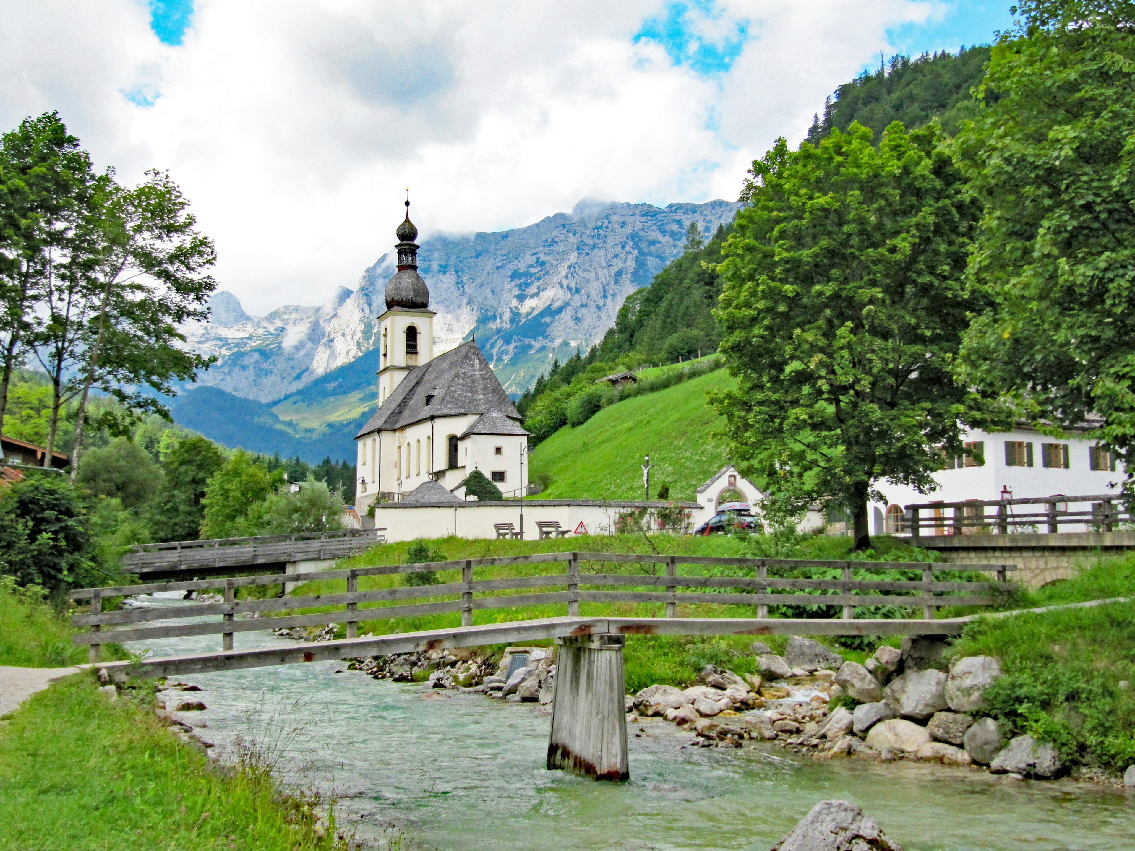 Affascinante chiesa circondata da alberi verdi e montagne