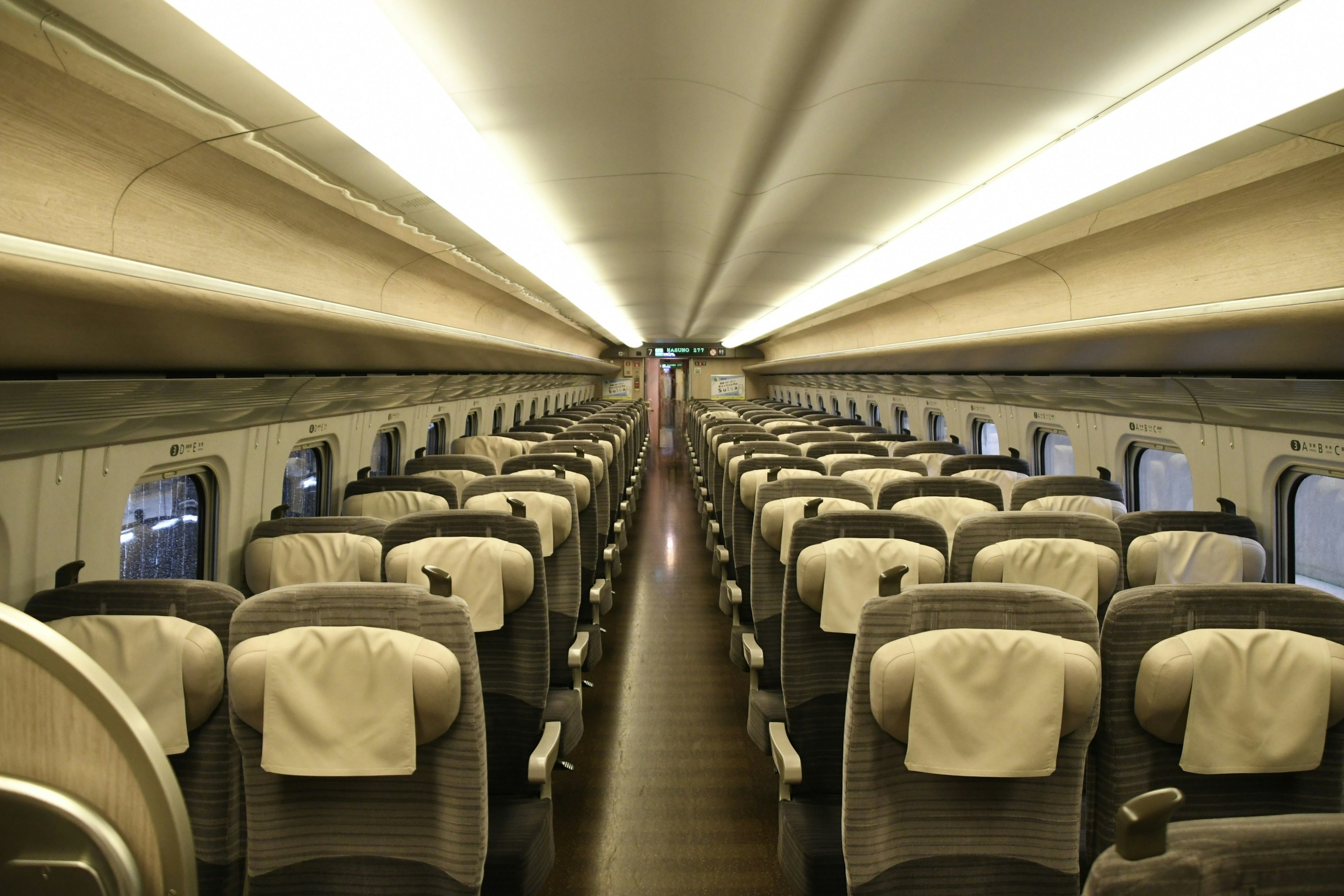 Interno di un treno Shinkansen con lungo corridoio e sedili