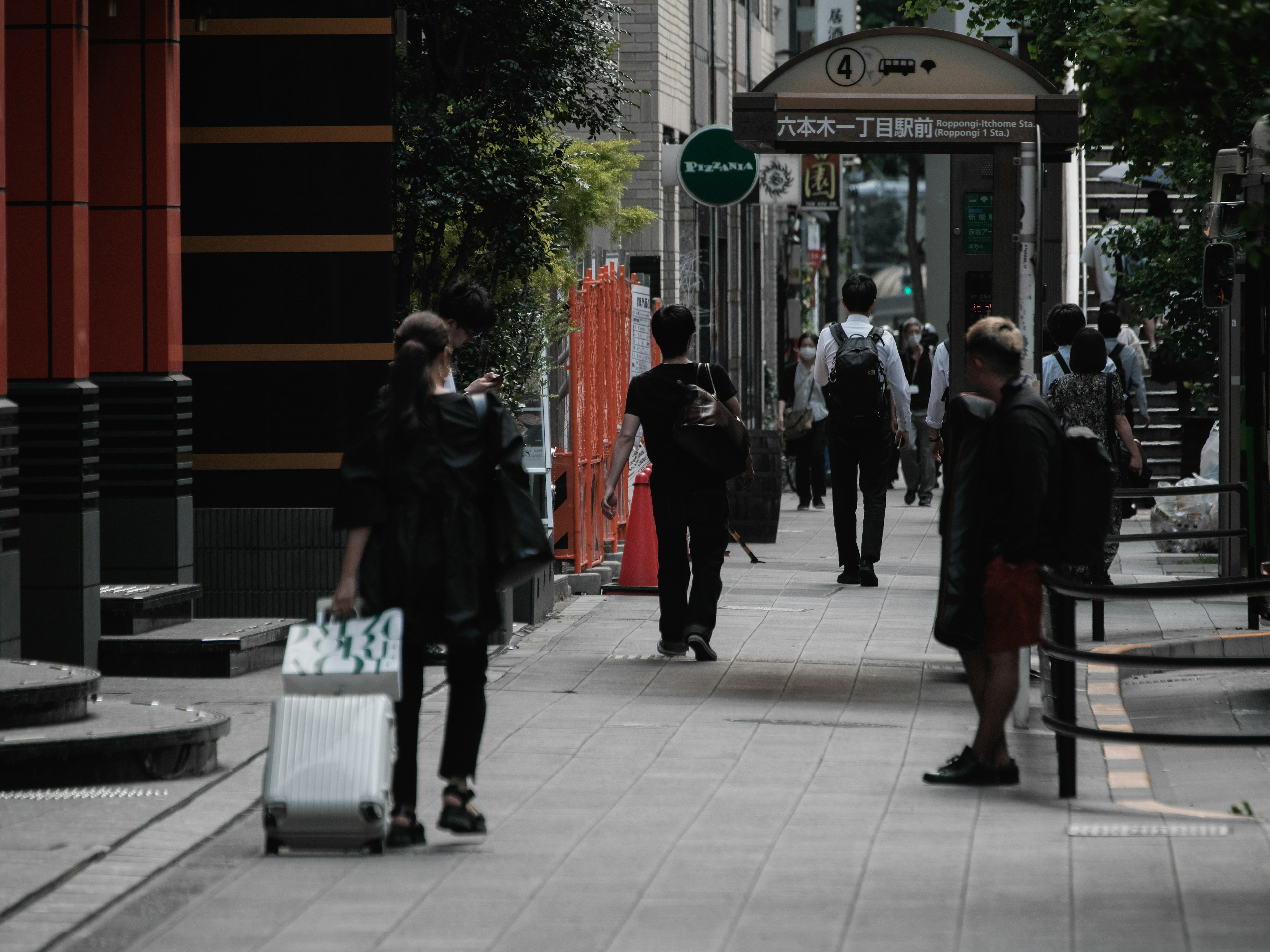 Eine Stadtstraße mit Menschen, die gehen, und einem Reisenden mit Gepäck