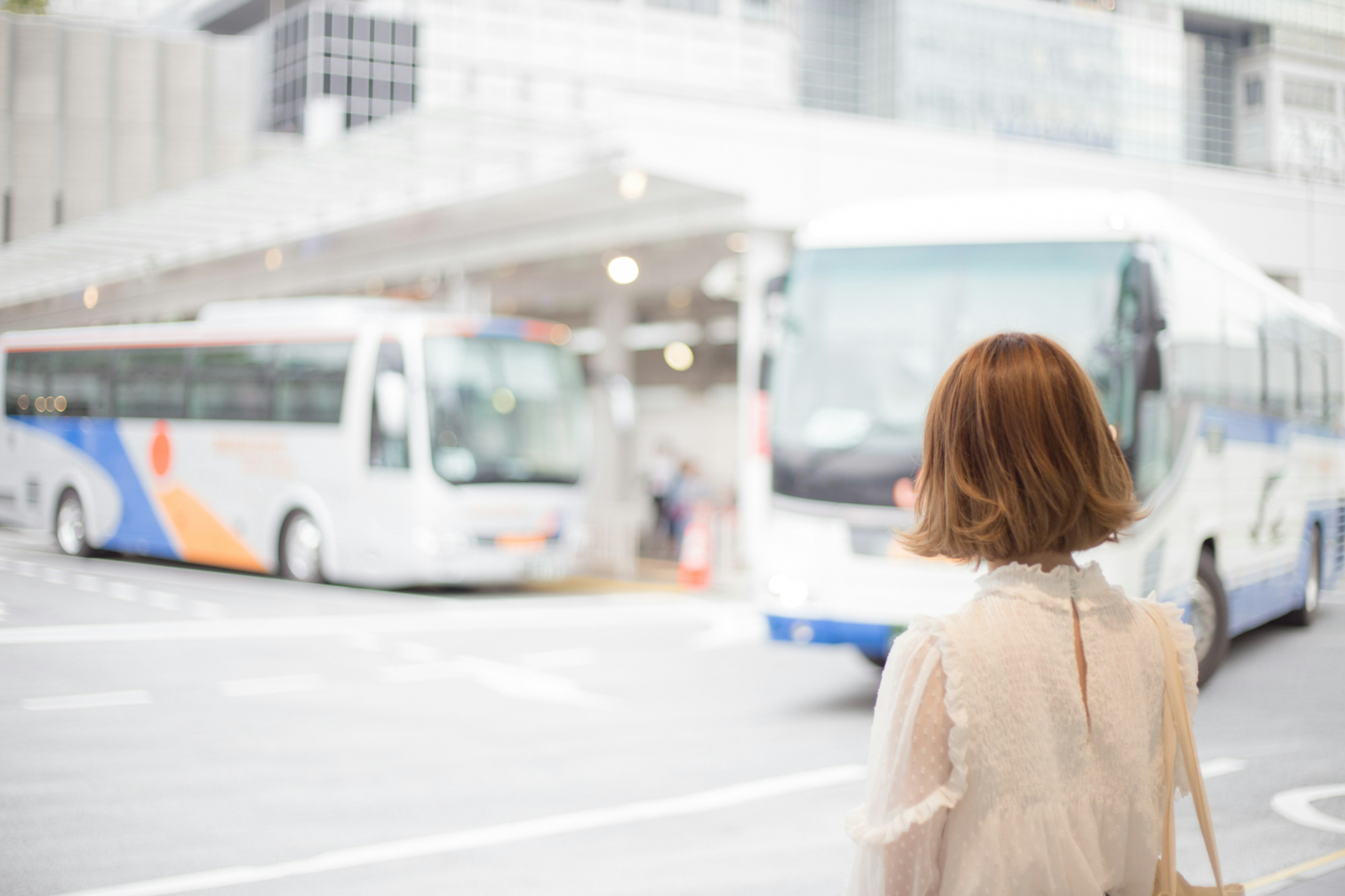 Eine Frau wartet an einer Bushaltestelle mit Bussen in Sicht