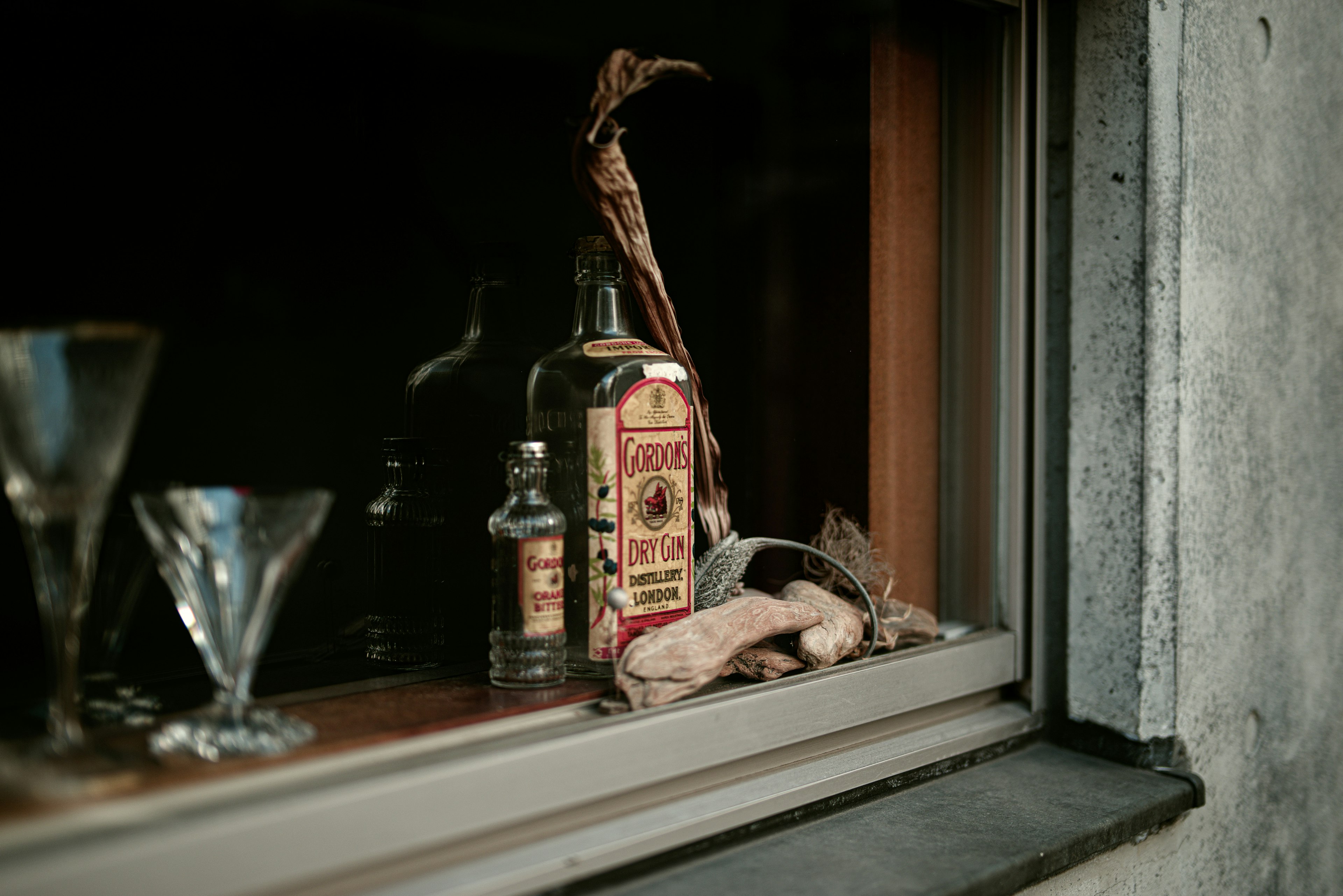 Naturaleza muerta de cristalería y botellas en un alféizar de ventana con estética vintage