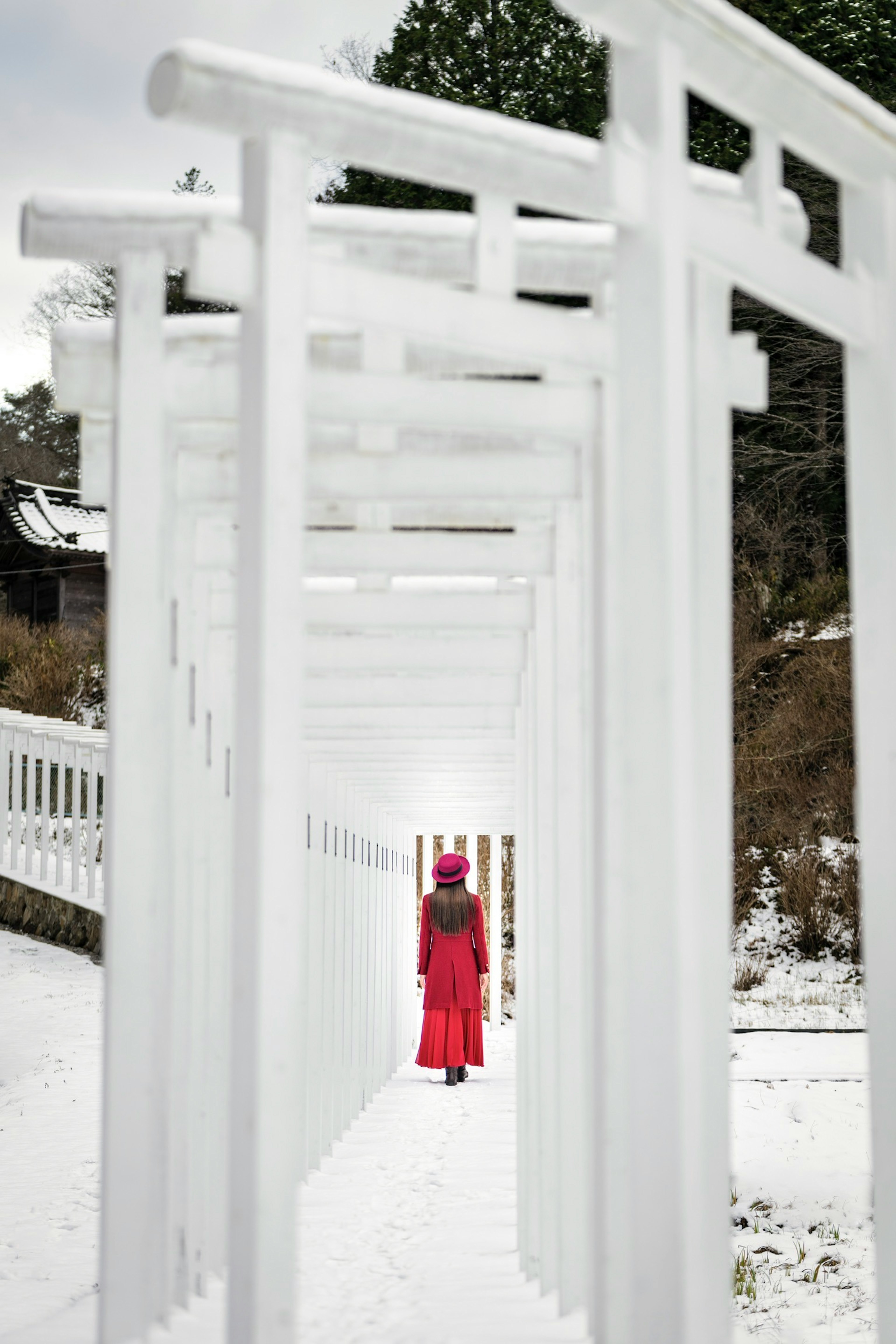 Una persona in abito rosso si trova in un tunnel di archi bianchi innevati