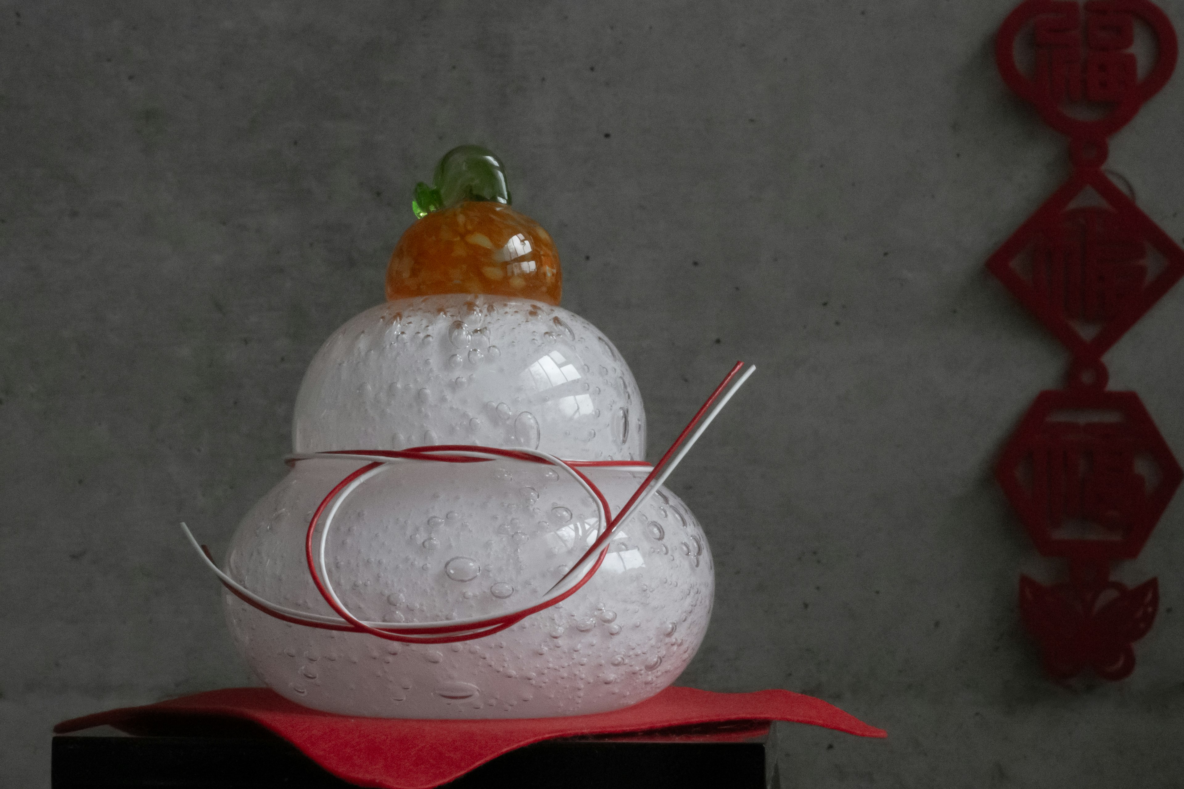 A decorative snowman made of white material with an orange top and red ribbon