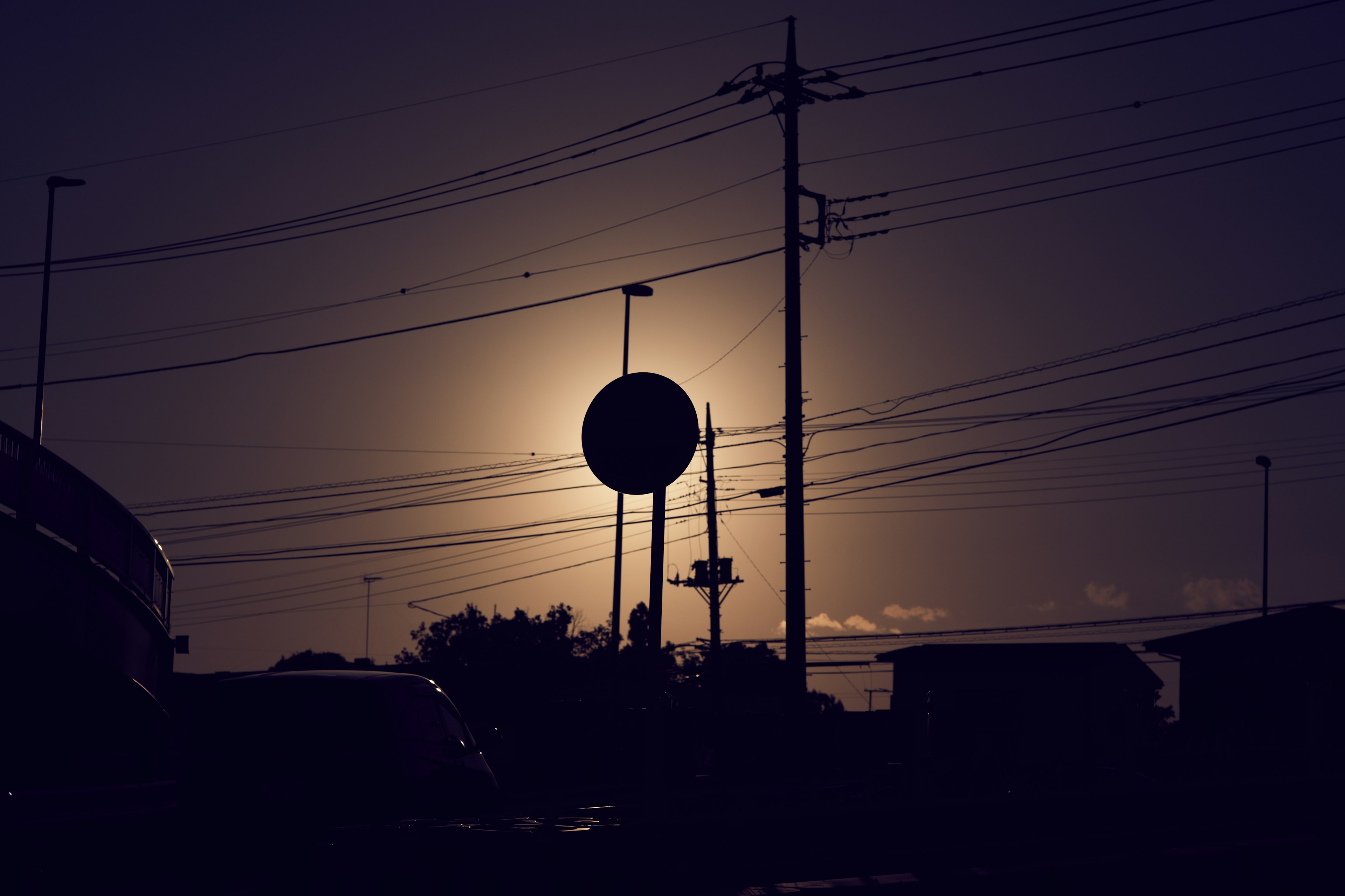 Silhouette d'un panneau et de poteaux électriques au coucher du soleil