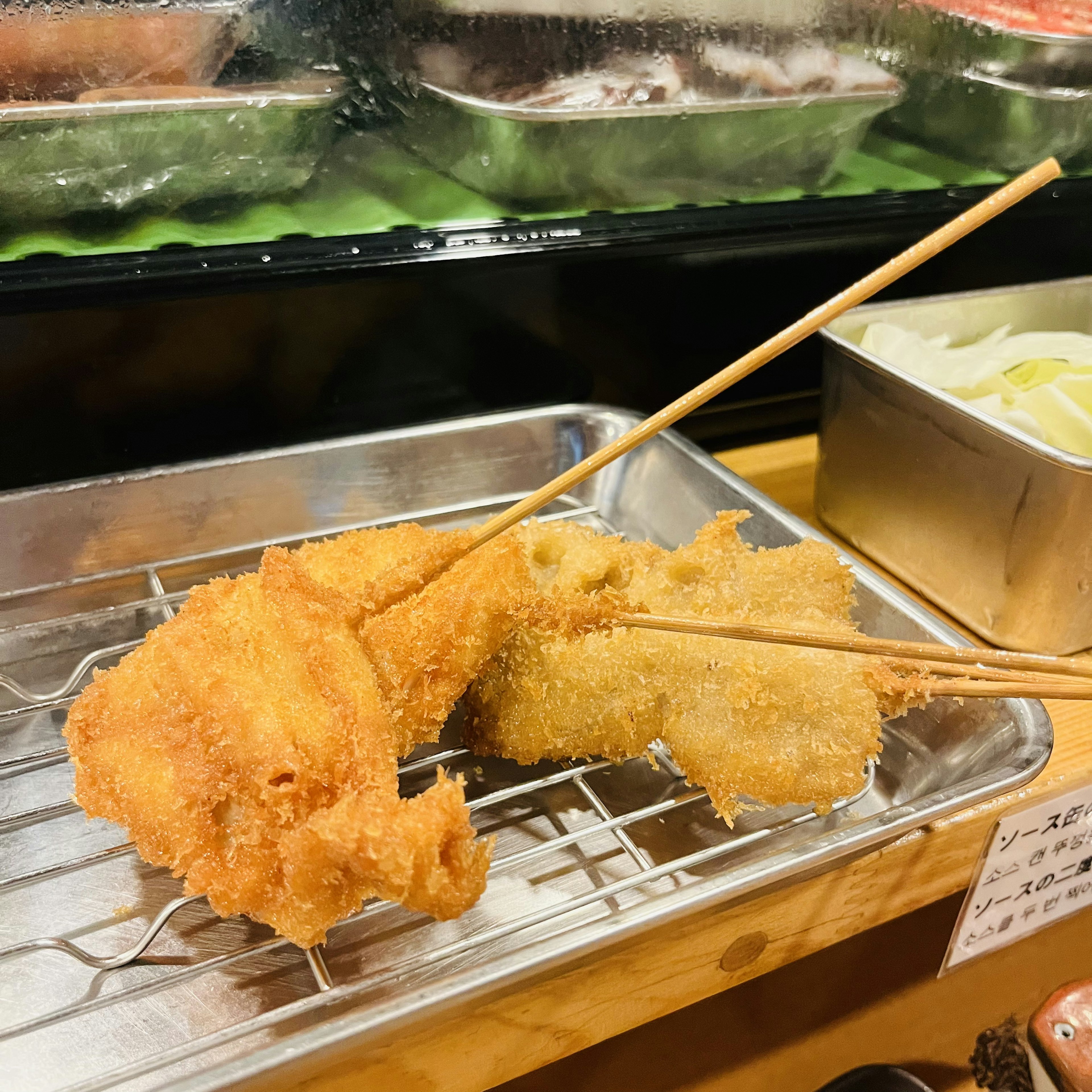 Two skewered fried items on a metal rack