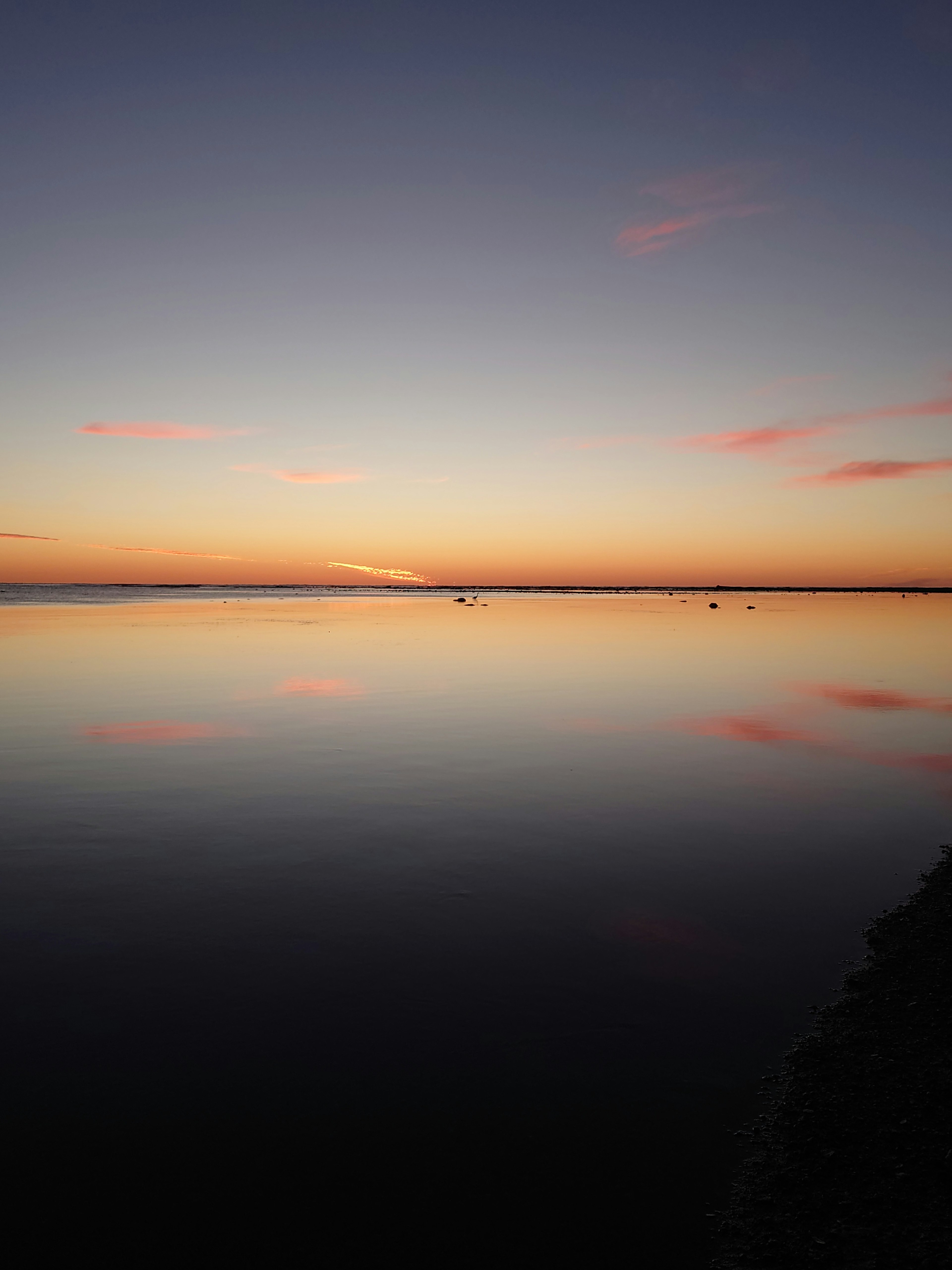 Lago calmo che riflette il cielo al tramonto e le nuvole