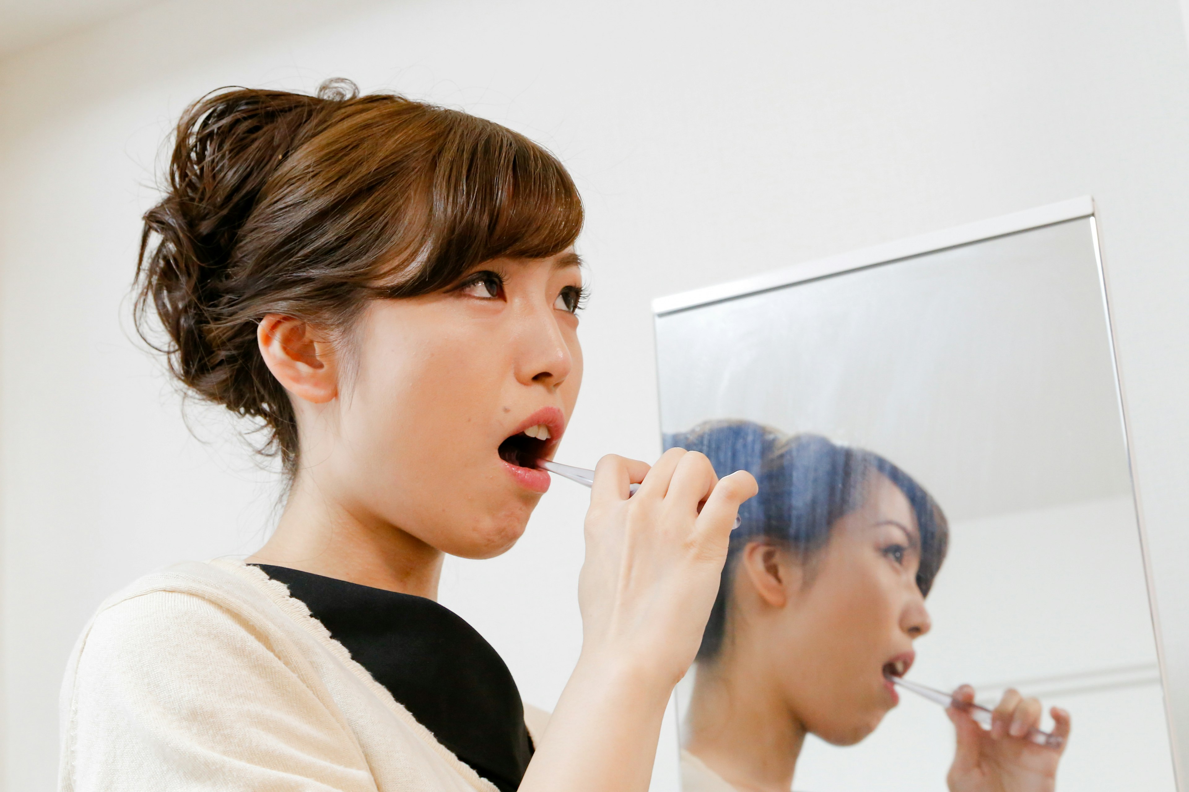 Woman brushing her teeth in front of a mirror