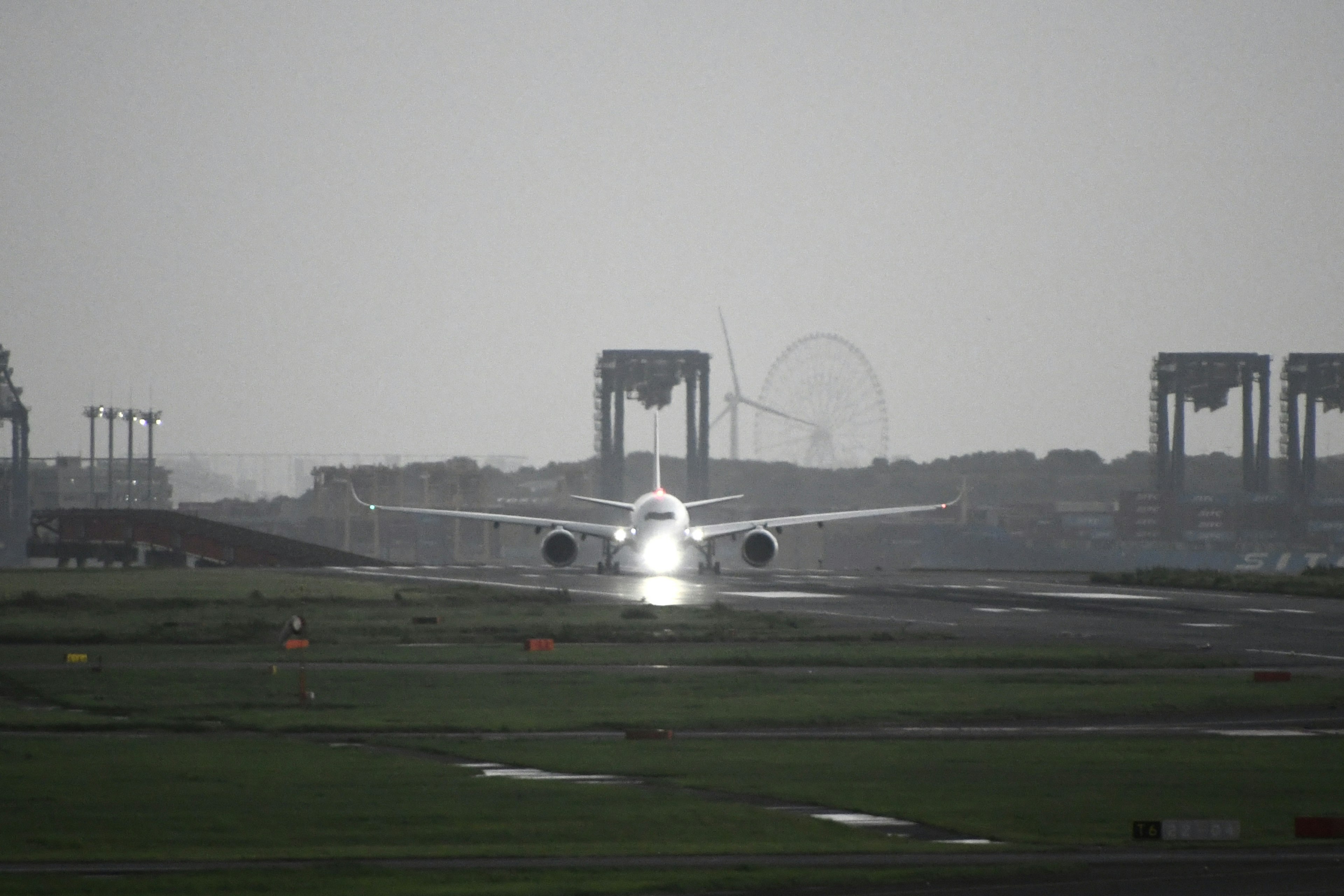 滑走路で着陸する航空機と背景のクレーン