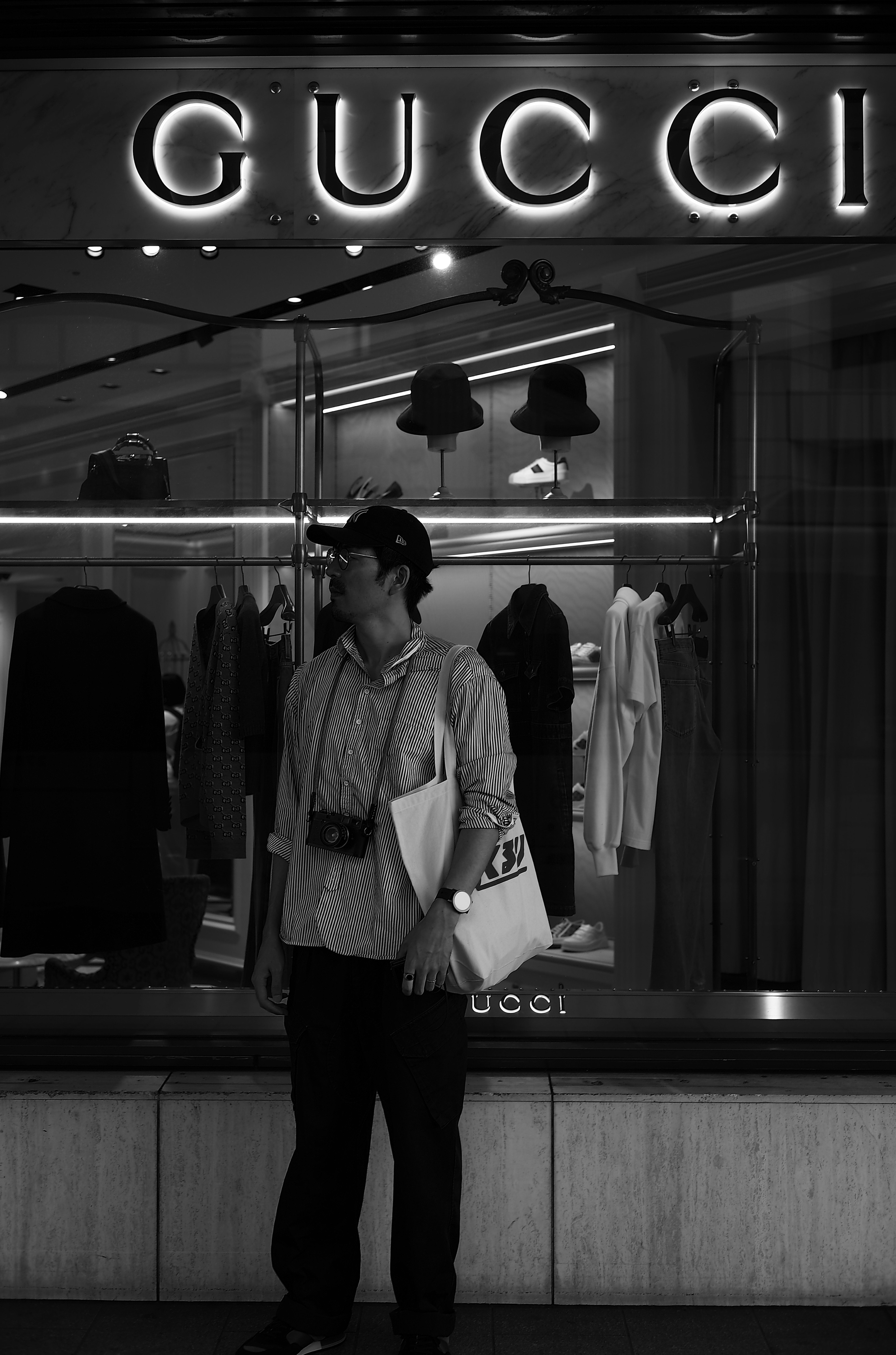 Foto en blanco y negro de una persona frente a una tienda GUCCI