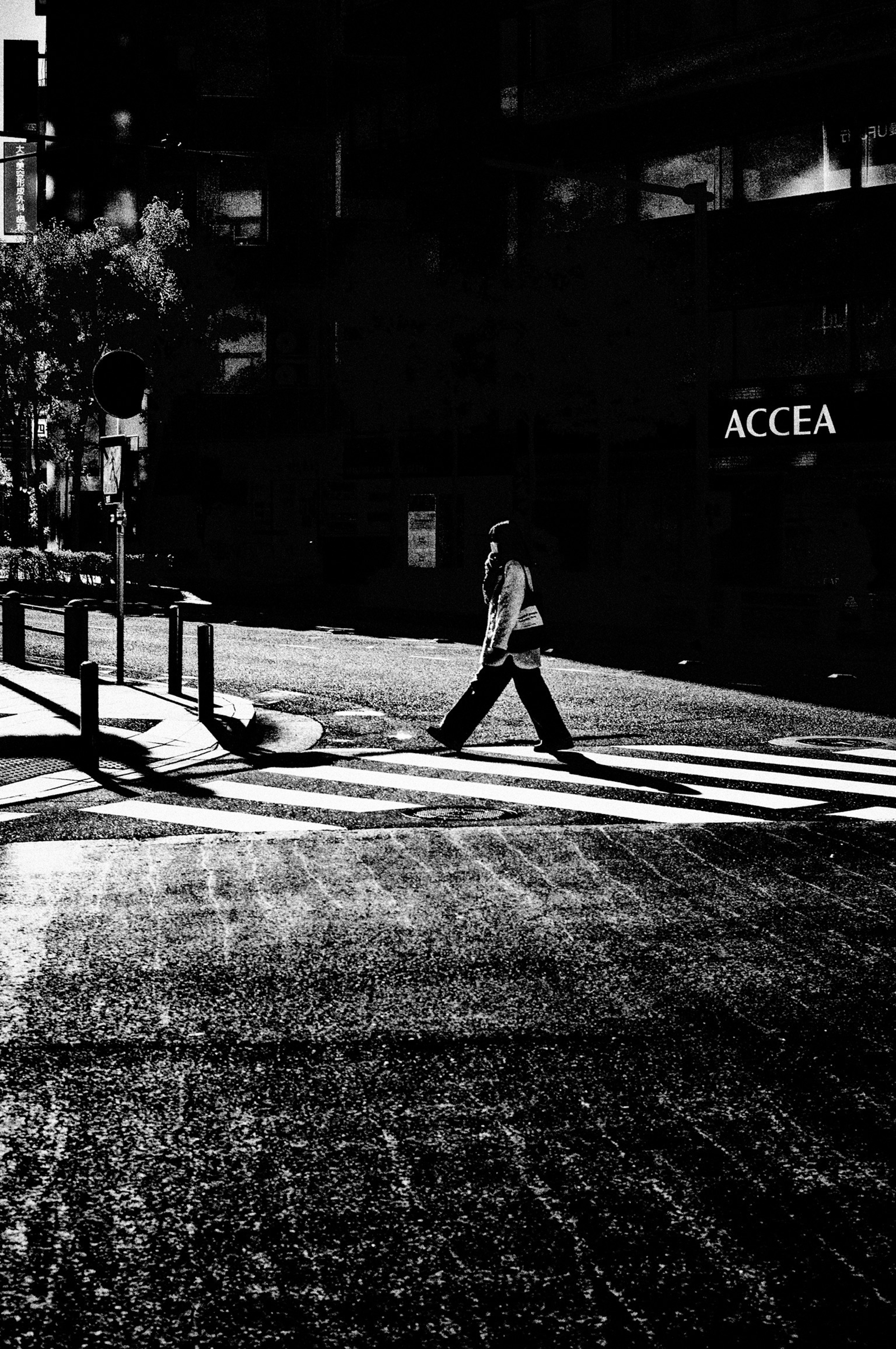 Una silhouette di una persona che cammina su un attraversamento pedonale in un angolo di strada in bianco e nero ad alto contrasto