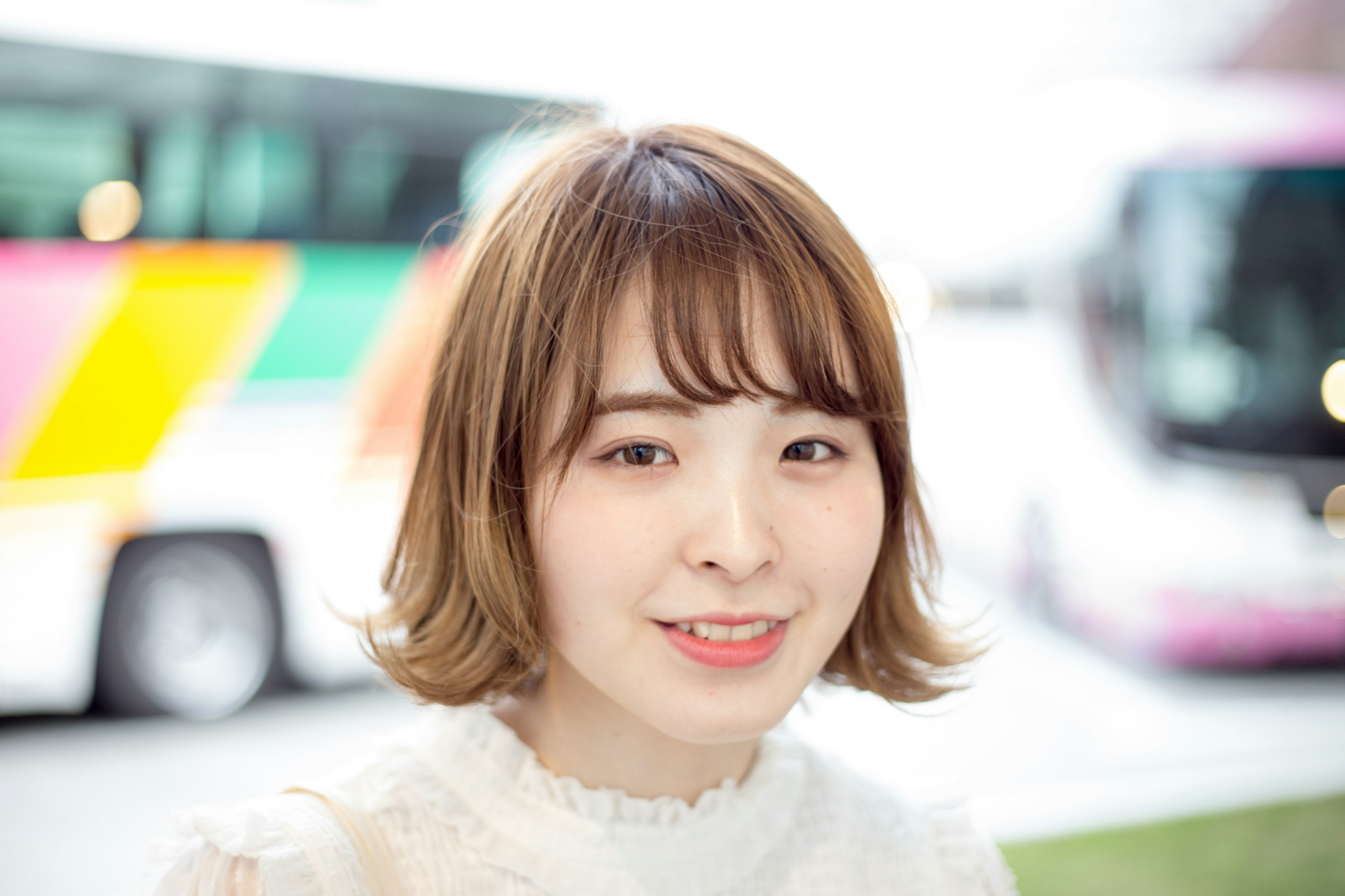 Une femme souriante avec une coiffure mignonne devant des bus colorés