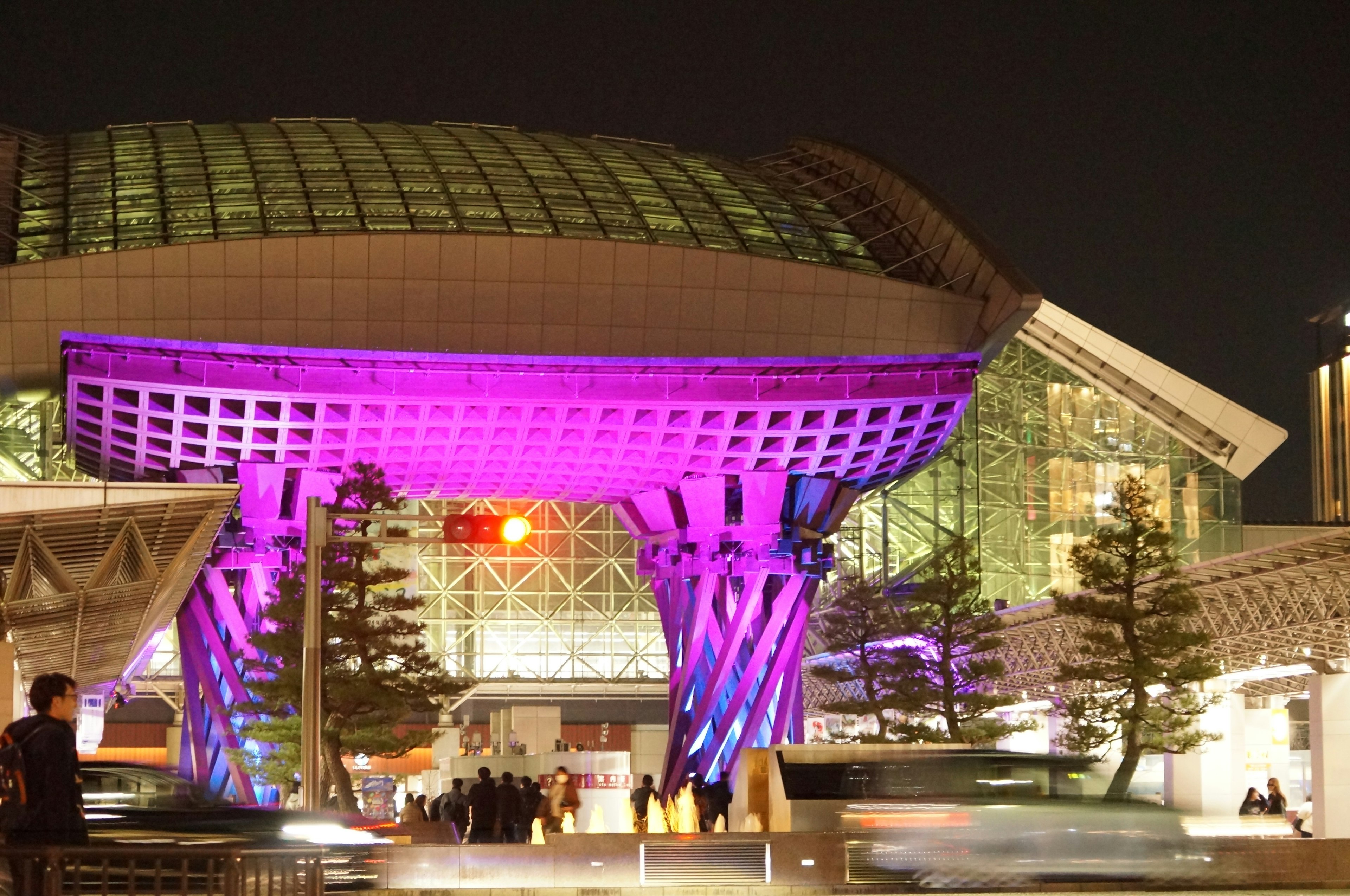 Gran estructura con iluminación morada en una estación de tren por la noche