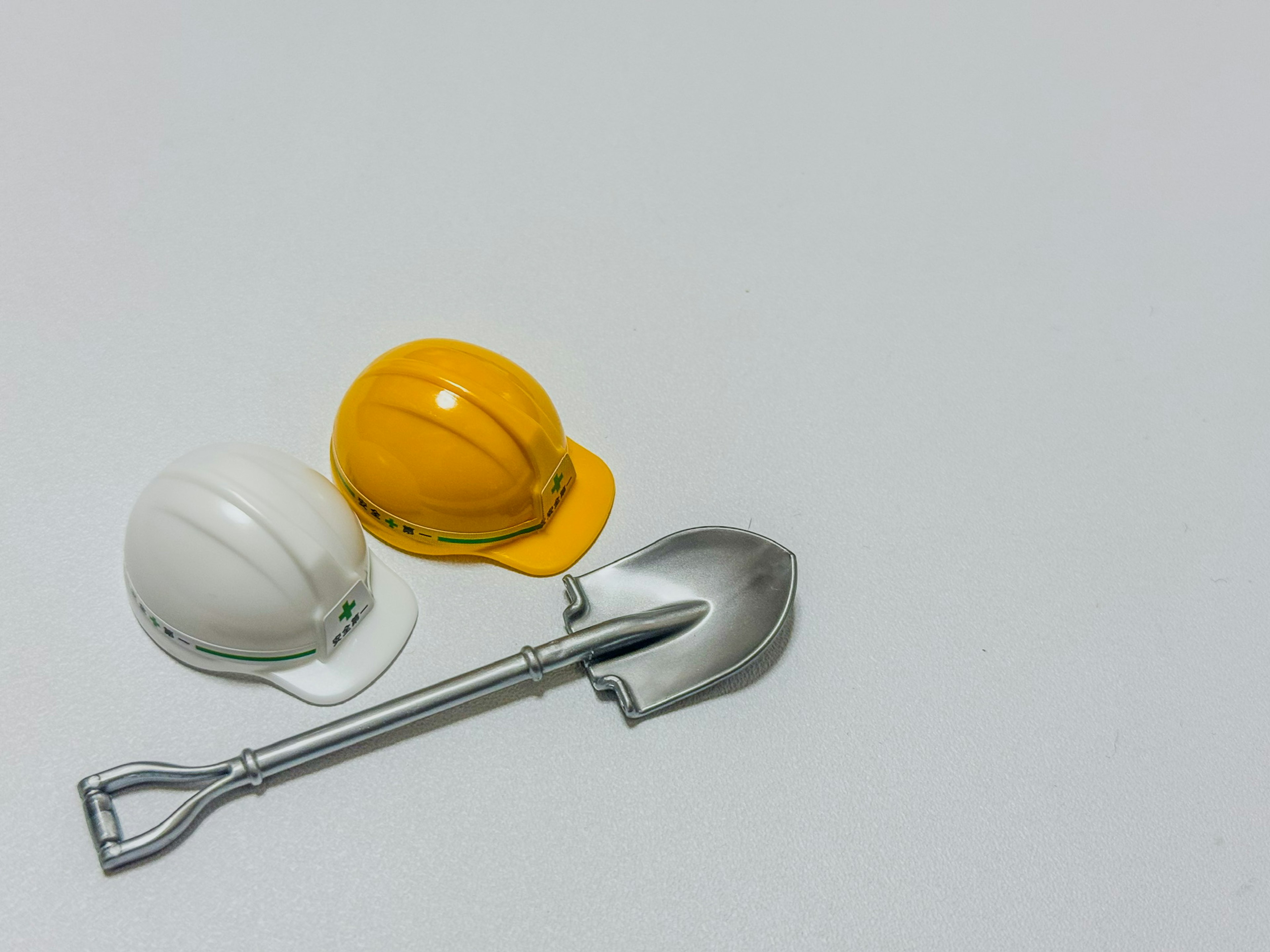 Disposición simple de un casco blanco y amarillo junto a una pala plateada