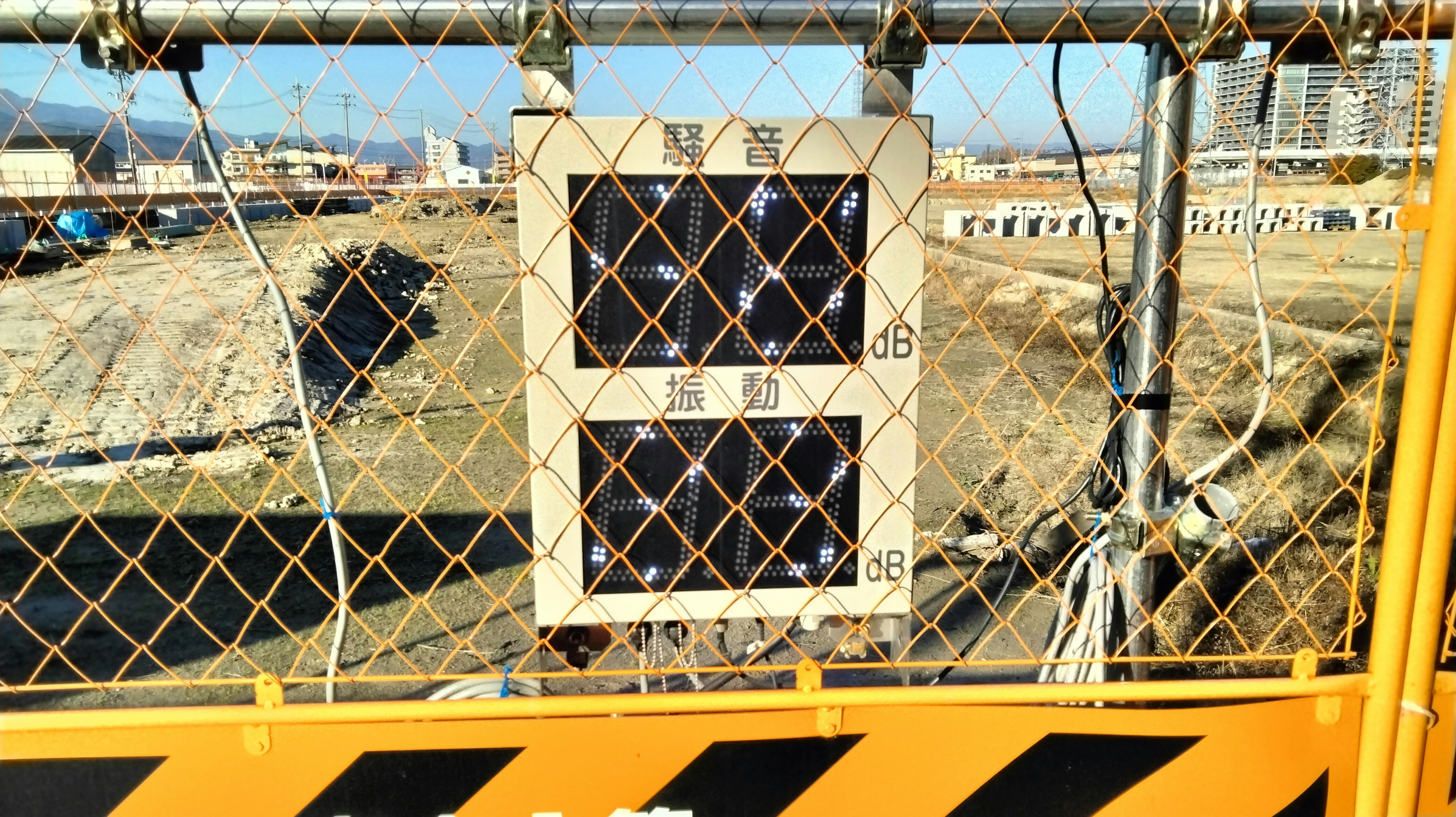 Safety board mounted on construction site fence with surrounding vacant land