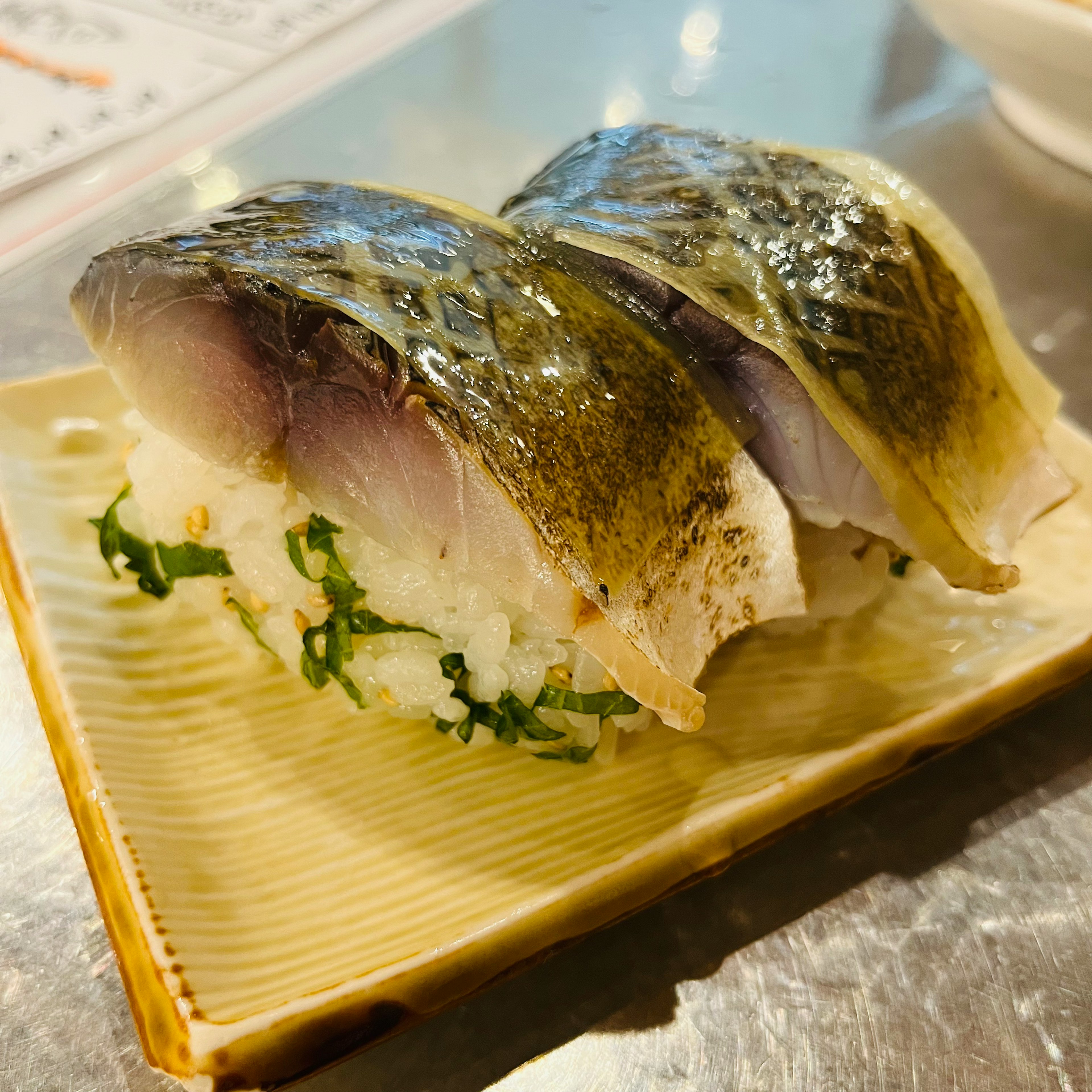 Due pezzi di sushi di pesce fresco serviti su una foglia verde