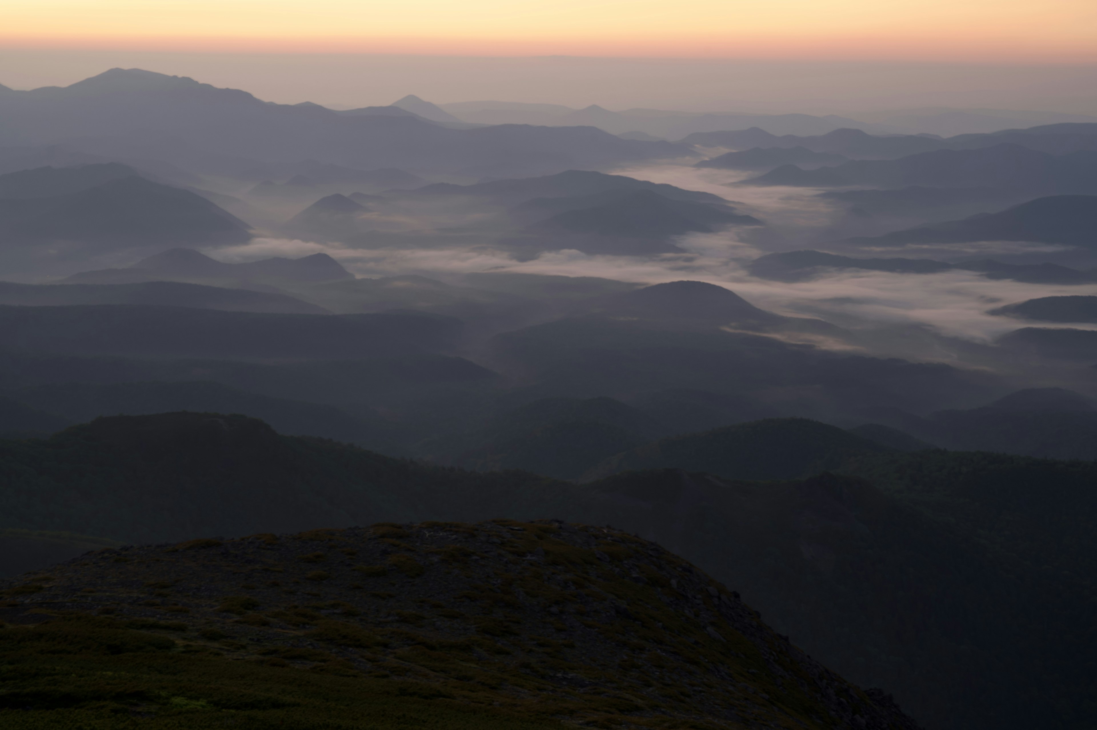 Paisaje montañoso dramático envuelto en niebla al atardecer