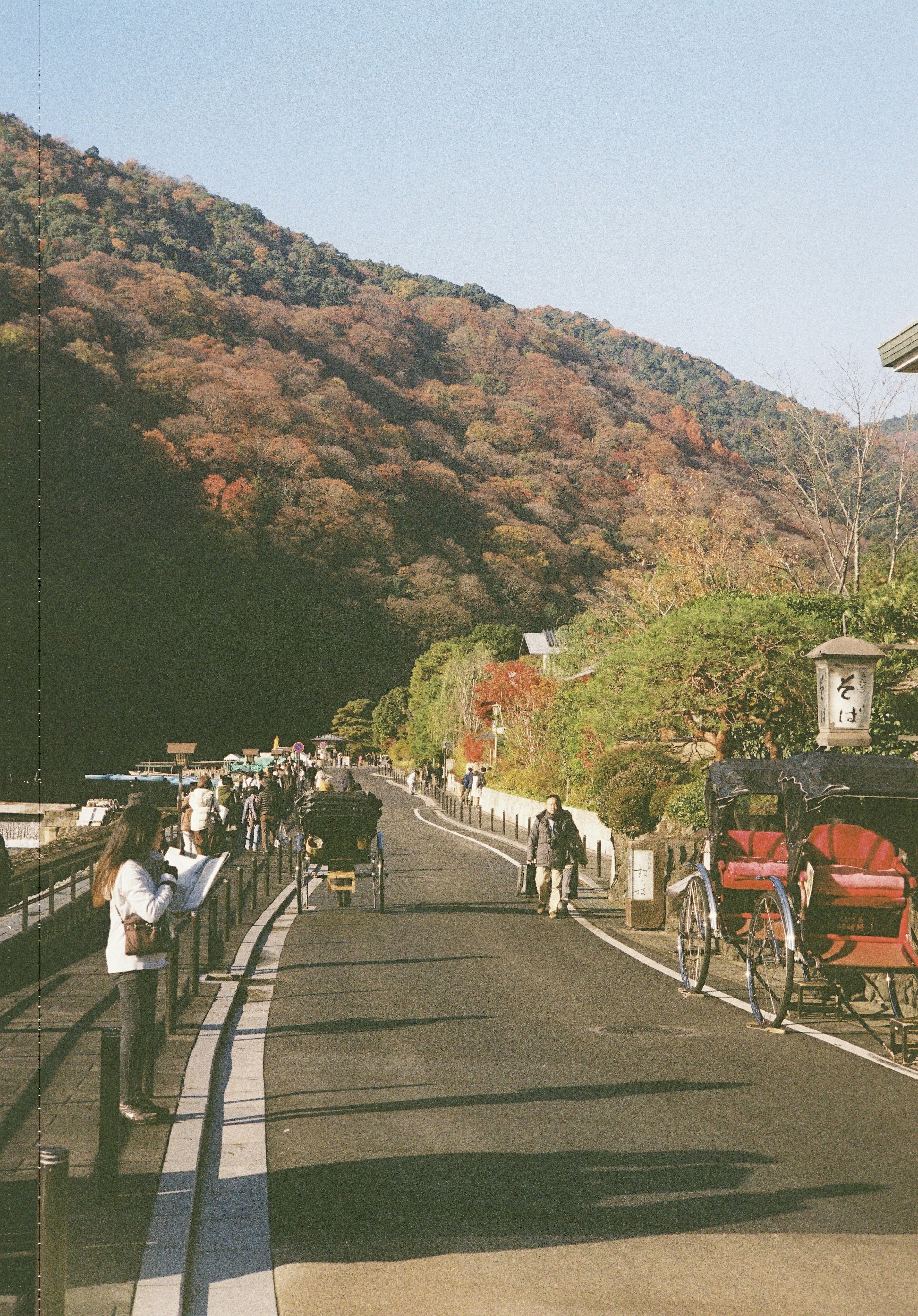 Scenic road with people walking and horse-drawn carriages surrounded by mountains