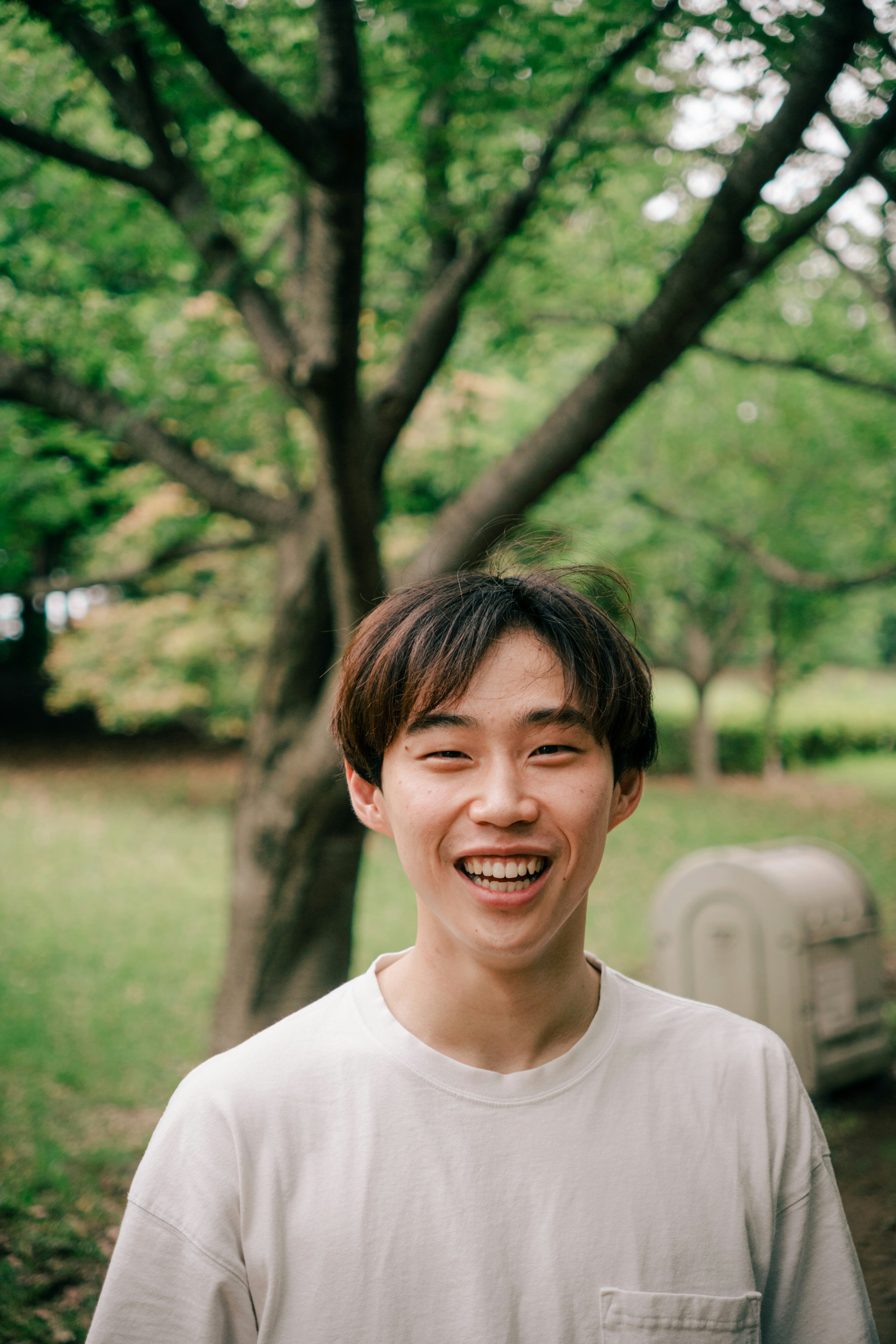 Retrato de un joven sonriente en un parque con árboles verdes de fondo