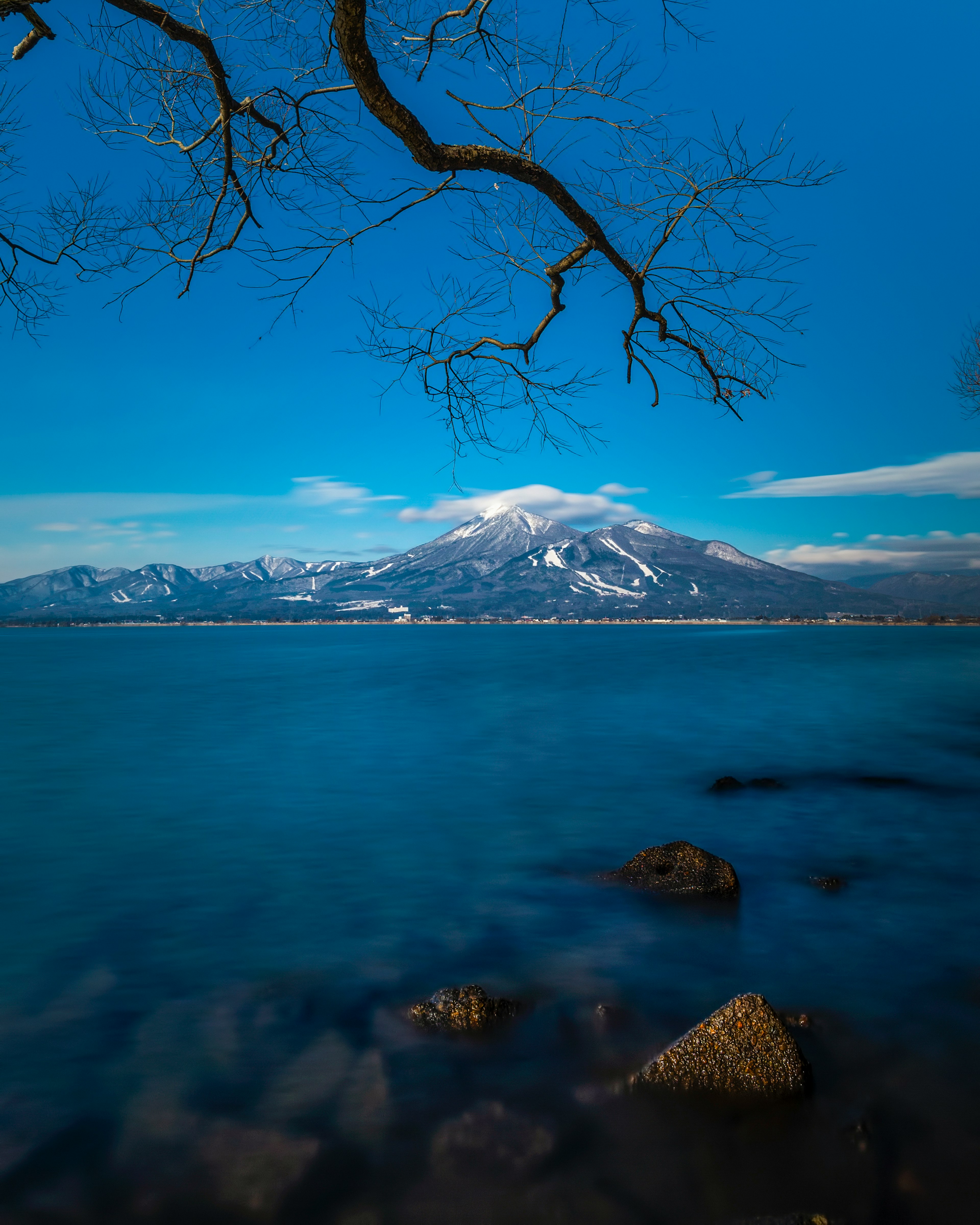 青い空の下に雪をかぶった山と静かな湖の風景