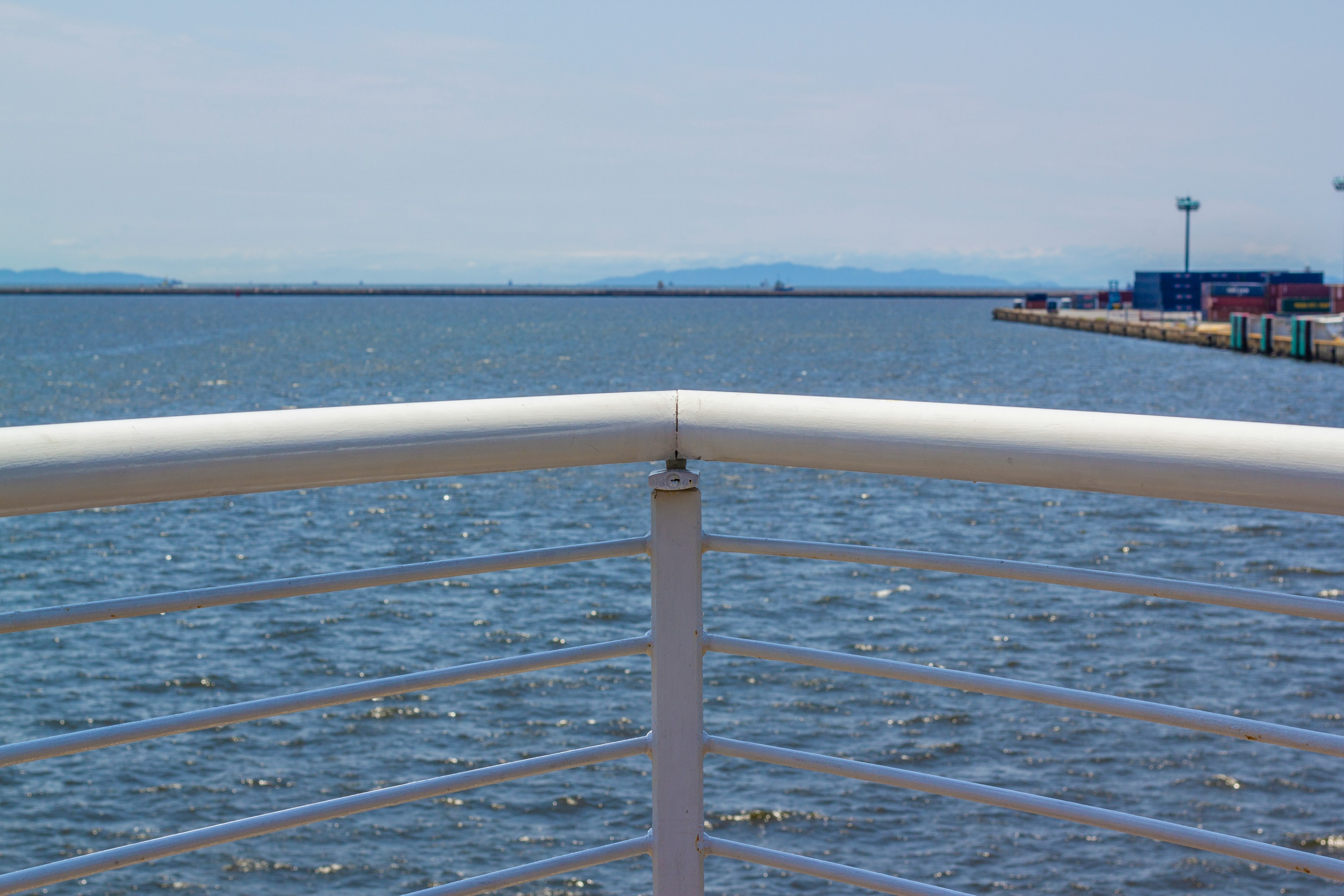 Vista del mare e del molo con una ringhiera bianca