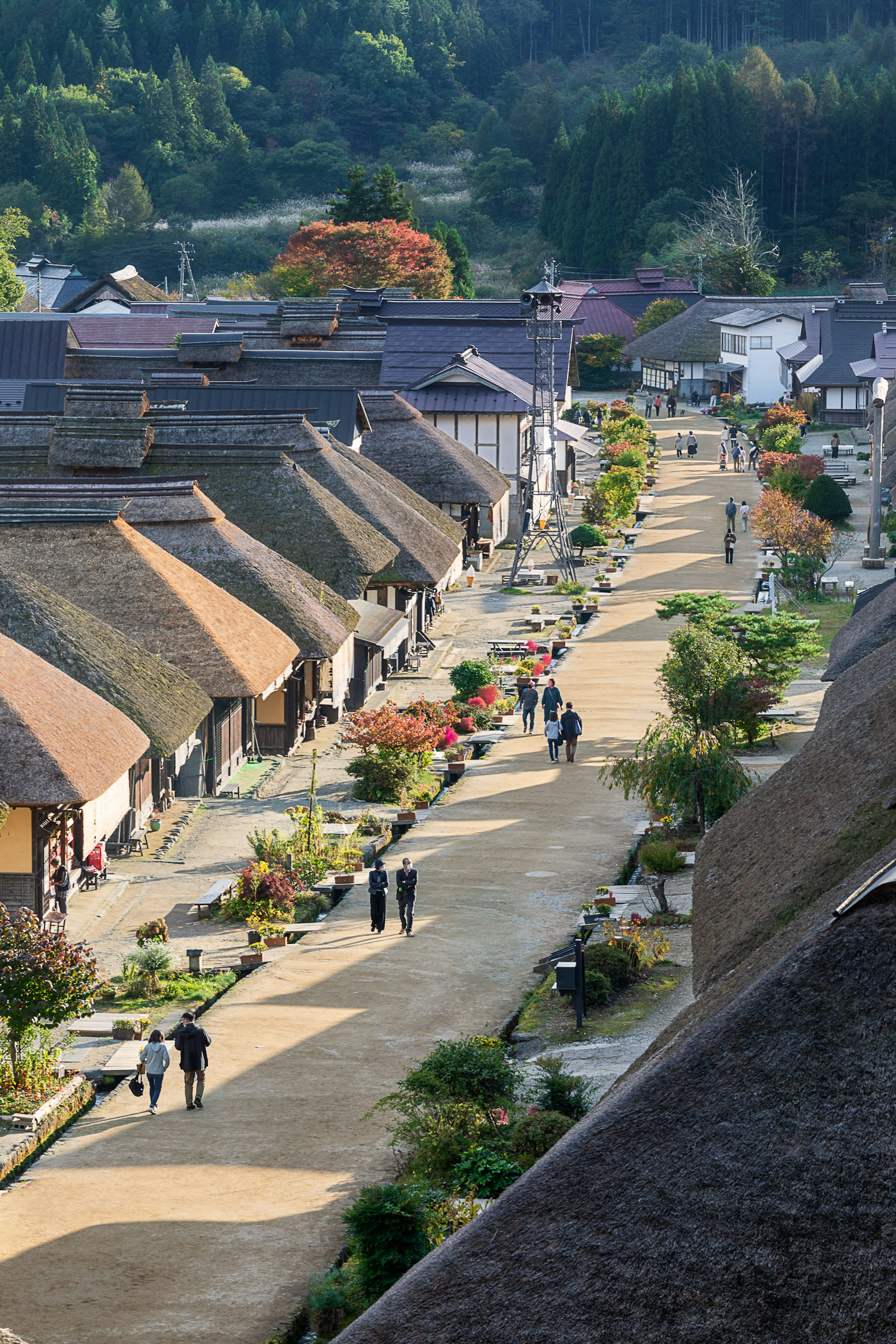 Scenic view of a traditional Japanese village with thatched-roof houses and people walking