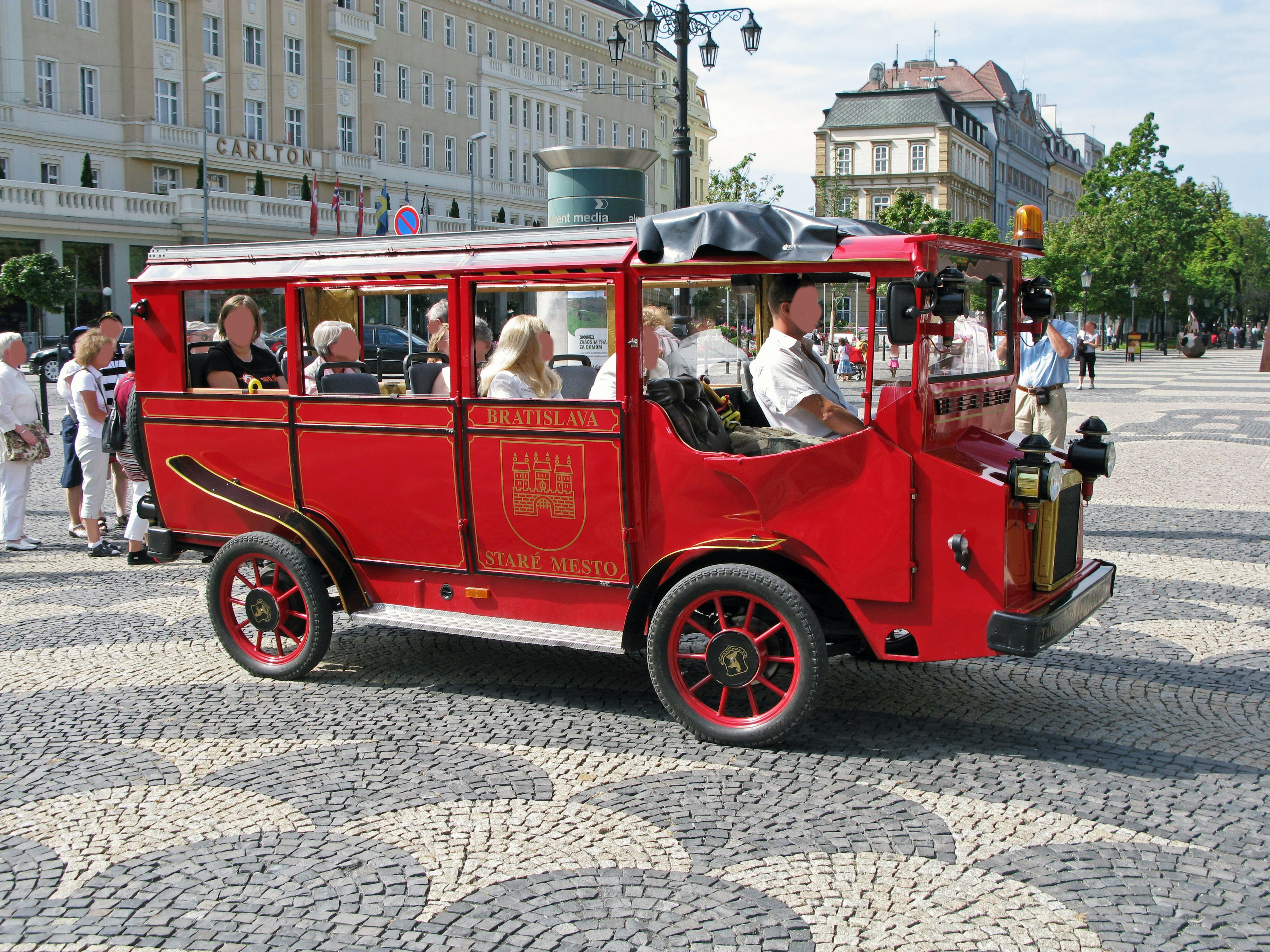 Red tourist bus driving through a square