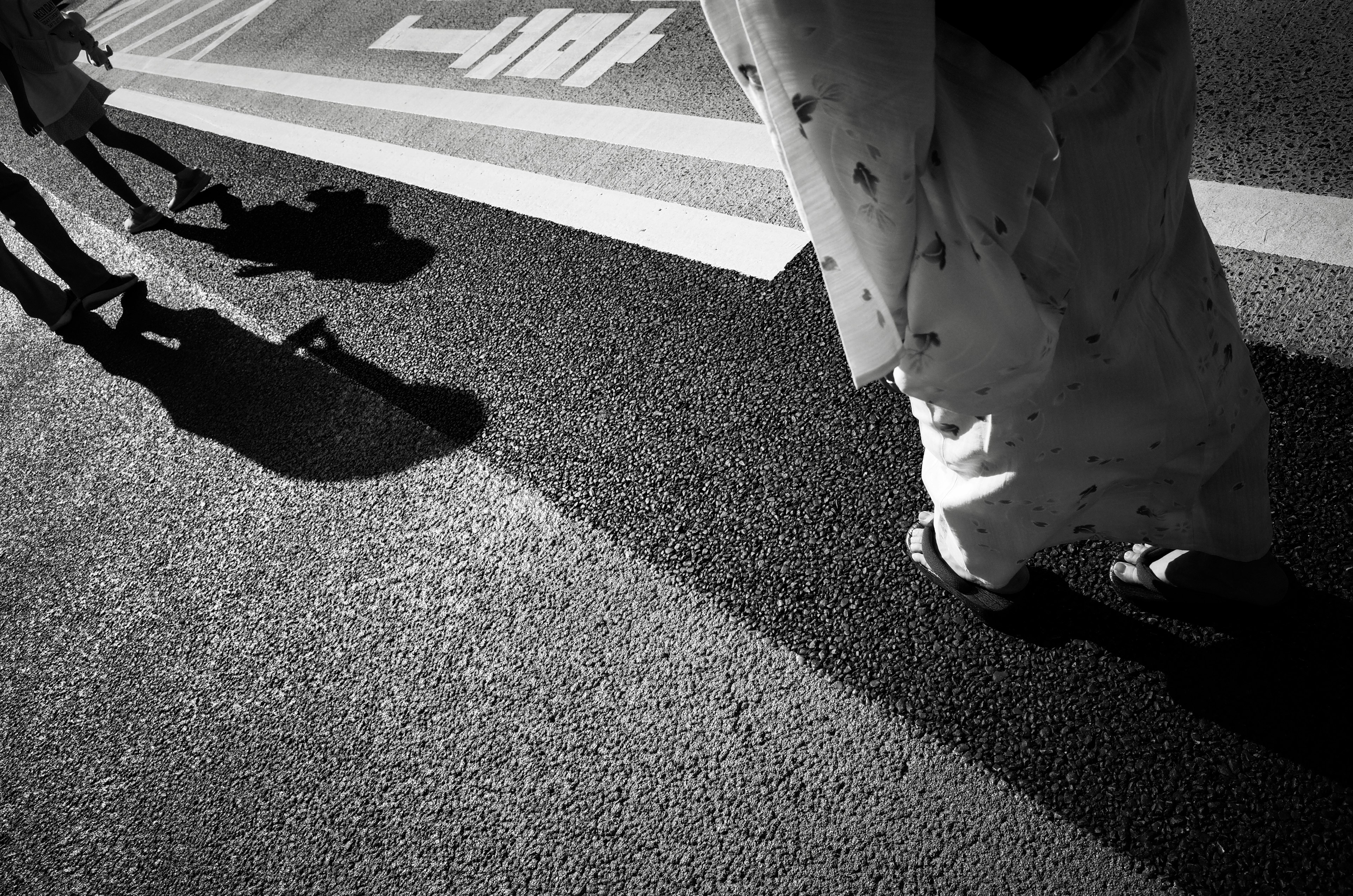 Shadows and clothing details of people walking on a black and white street