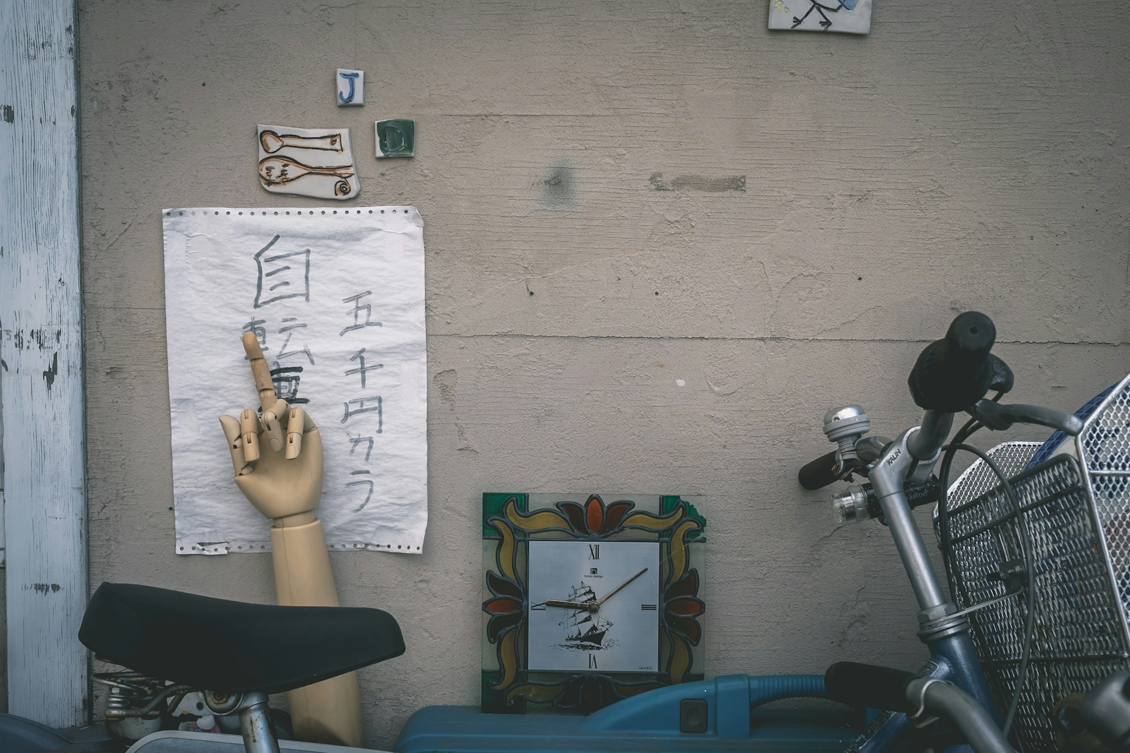 Un papel con escritura en una pared y un modelo de mano al lado de una bicicleta y un reloj