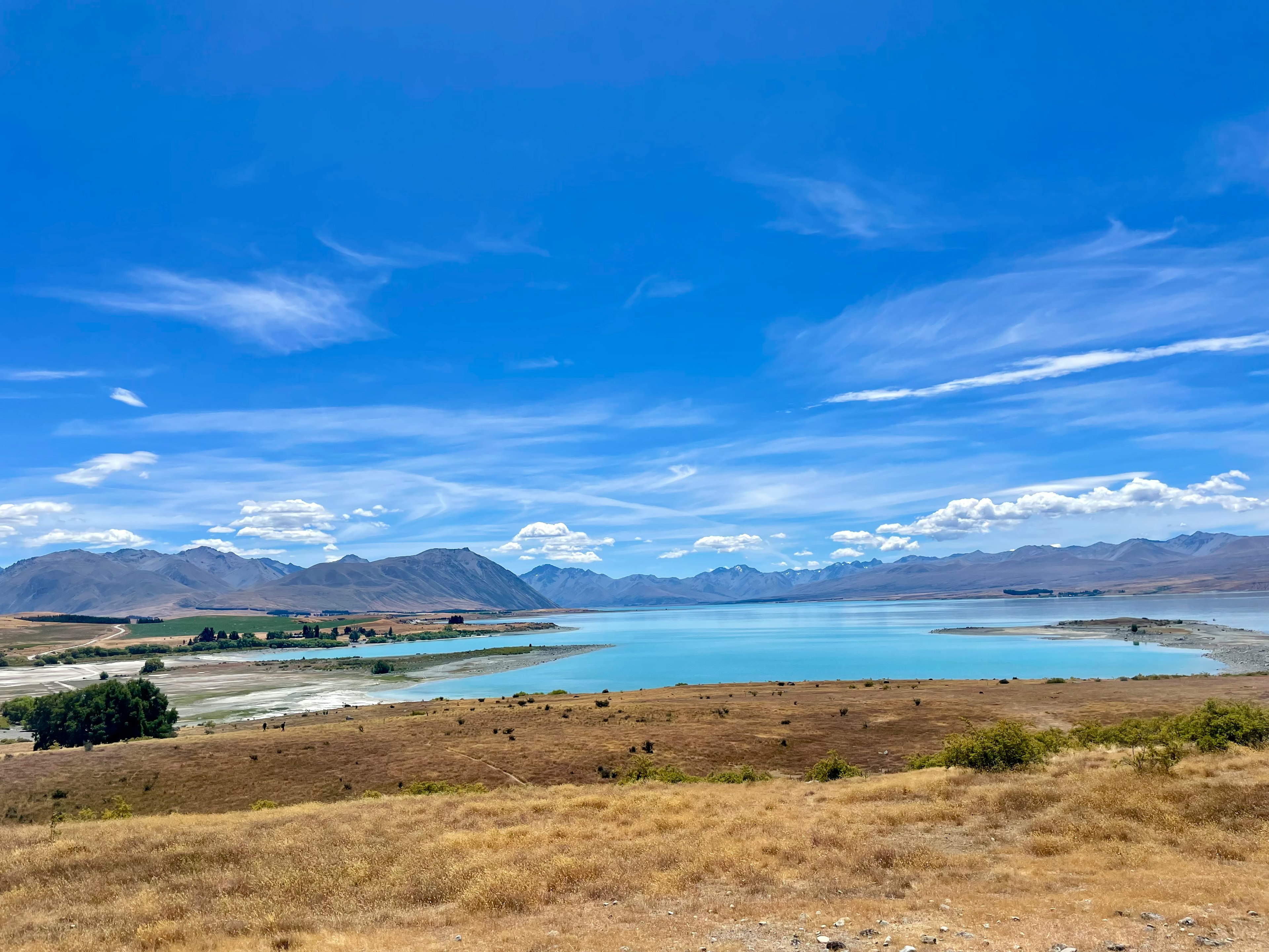 Une vue panoramique d'un lac bleu entouré d'herbe sèche et de montagnes