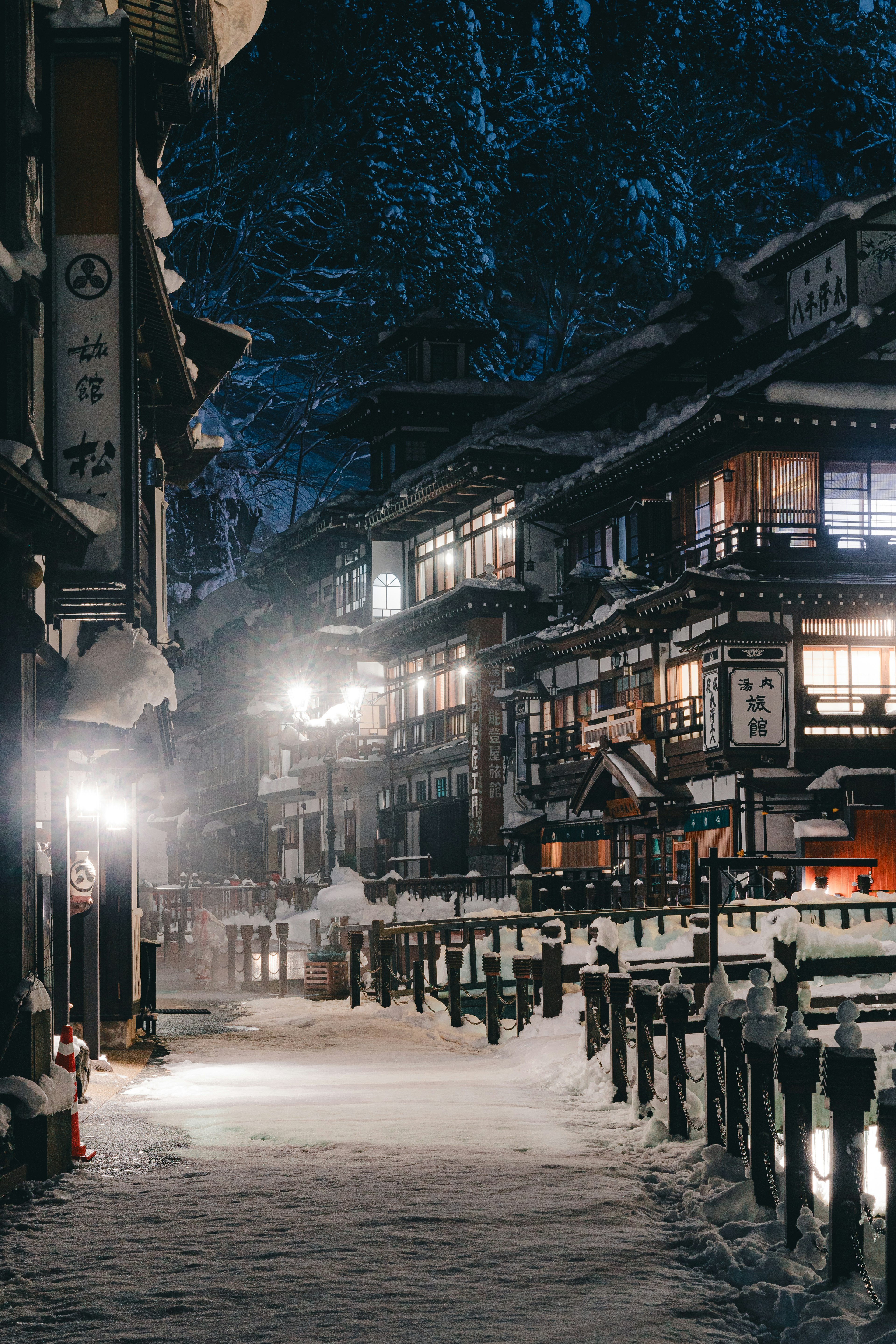 Quiet snow-covered street with traditional Japanese buildings and warm lights