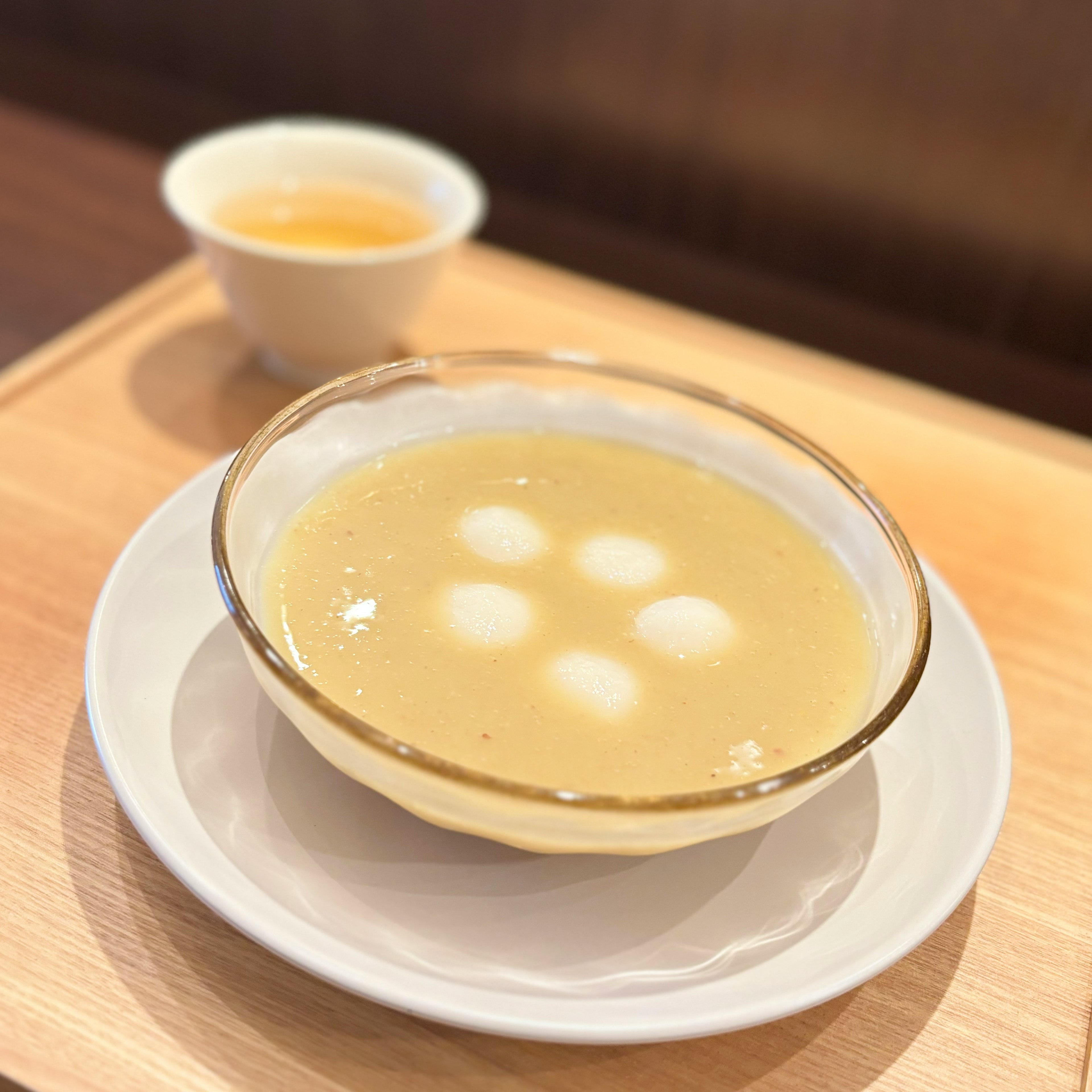 Schüssel mit warmer Suppe und weißen Klößen sowie einer Teetasse daneben